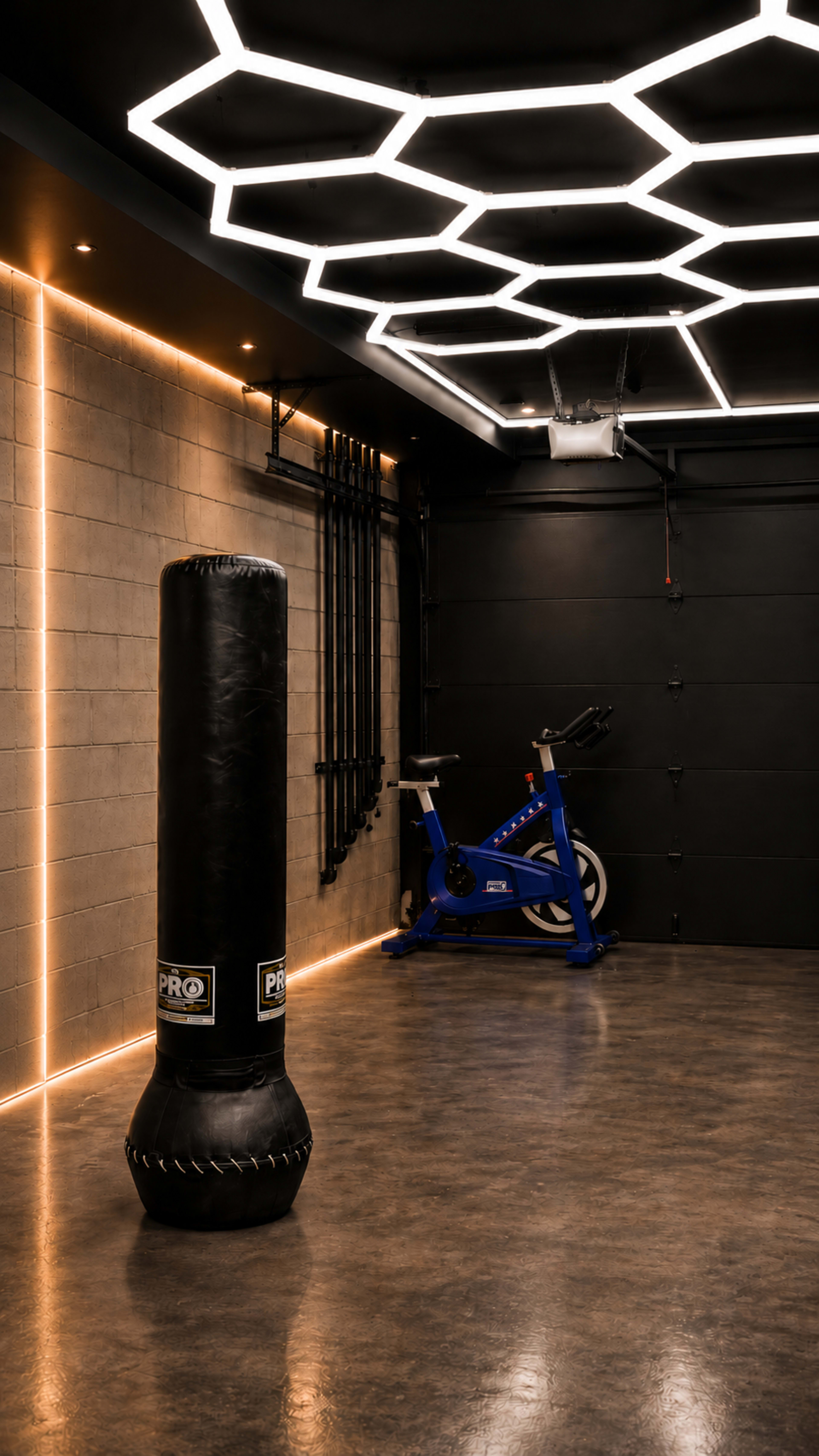 The image shows a modern fitness room with a punching bag, a stationary bike, and a geometric light fixture on the ceiling.
