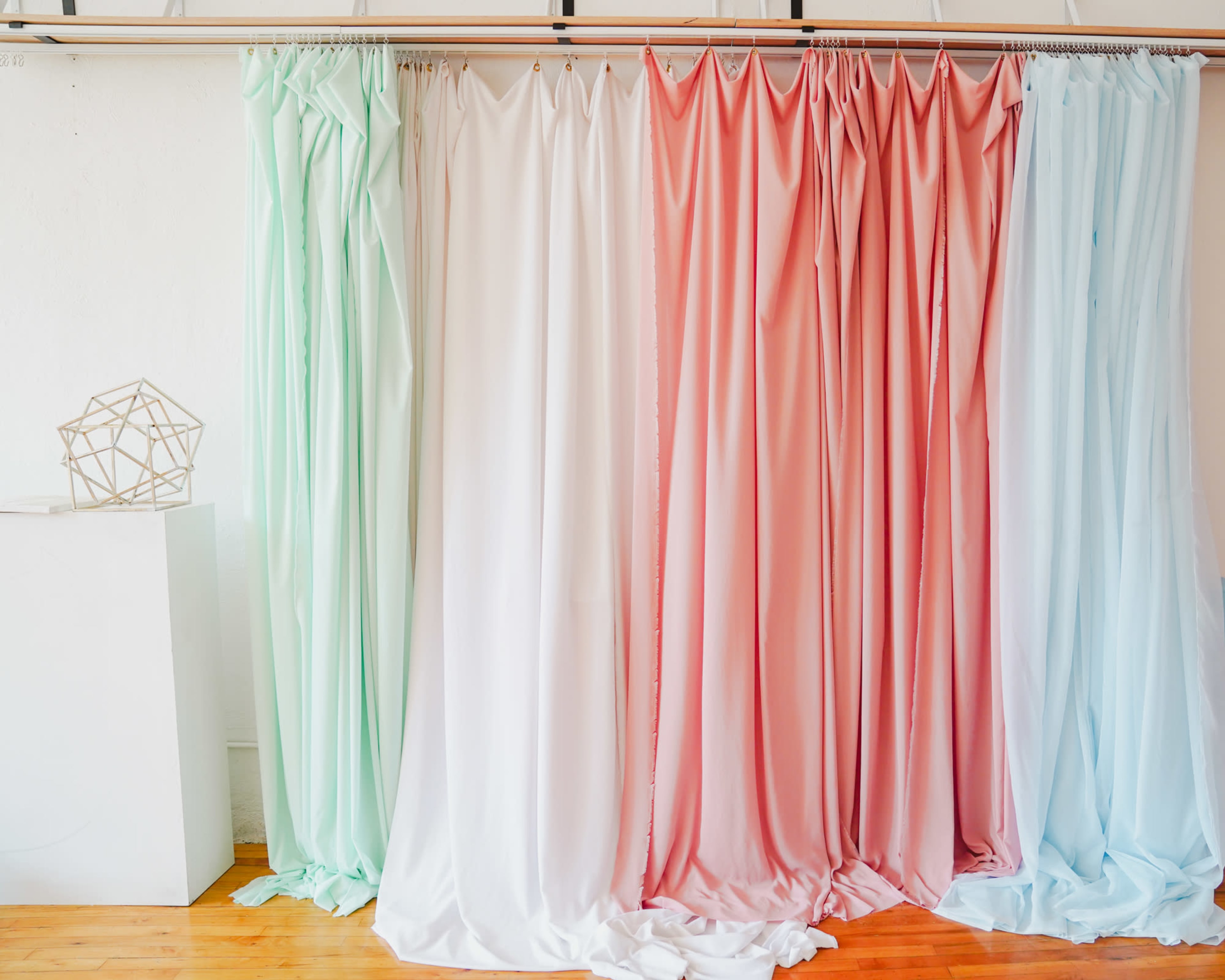 A display of draped fabric curtains in pastel colors arranged in vertical sections.