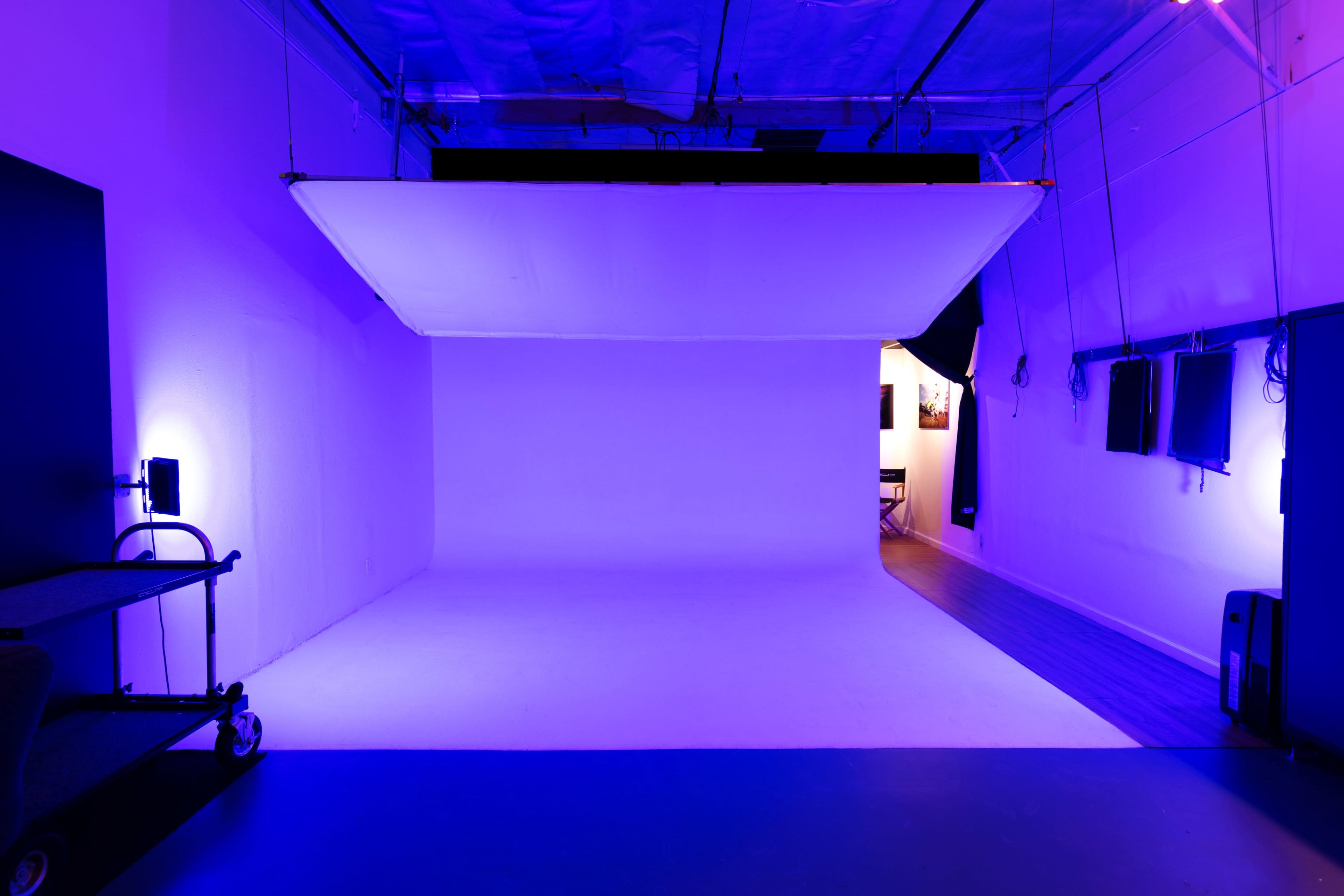 A photography studio with a large white backdrop and purple lighting.
