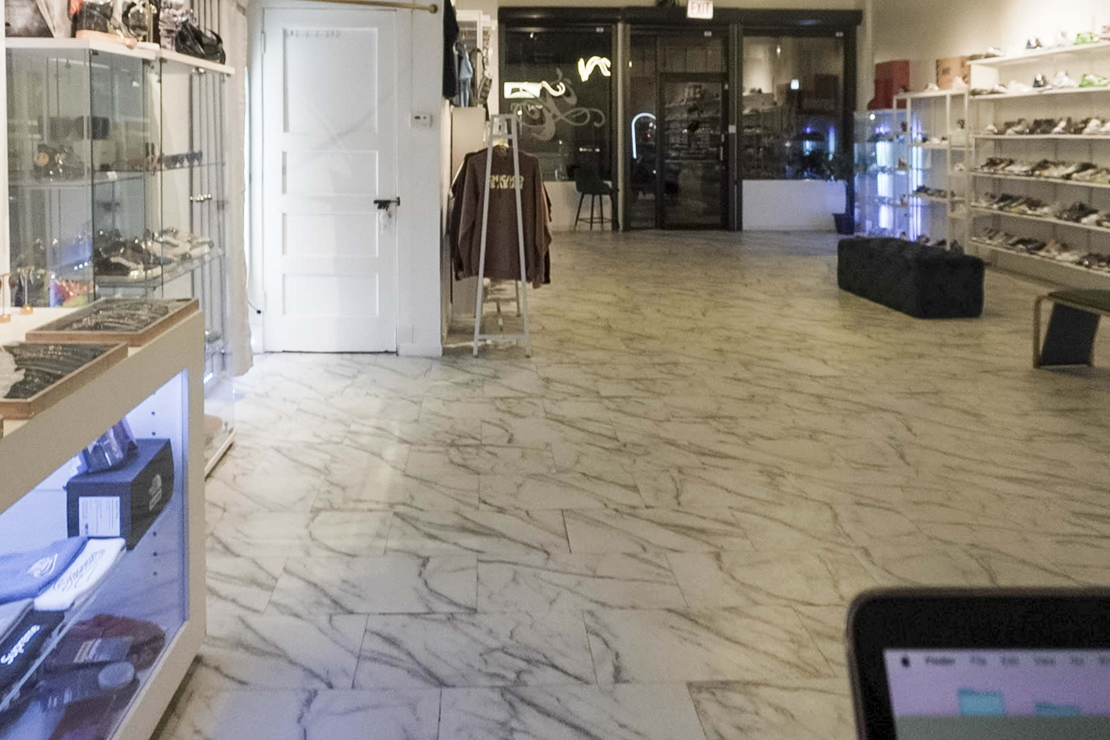 A spacious retail store with marble flooring, displaying various products in glass cases along the walls.