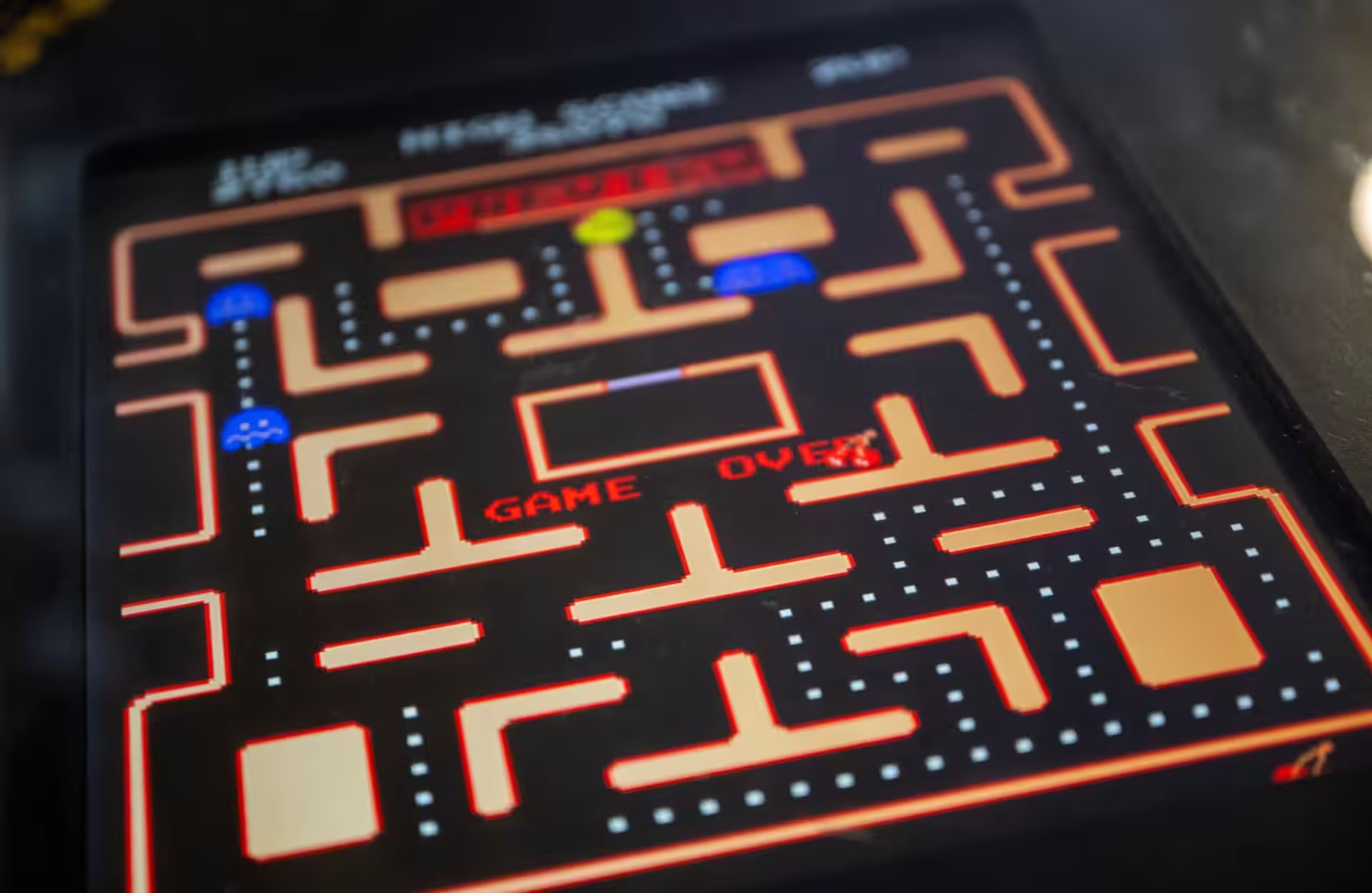The image shows a close-up of a classic arcade game screen displaying a "Game Over" message within a maze structure typical of a maze chase game.