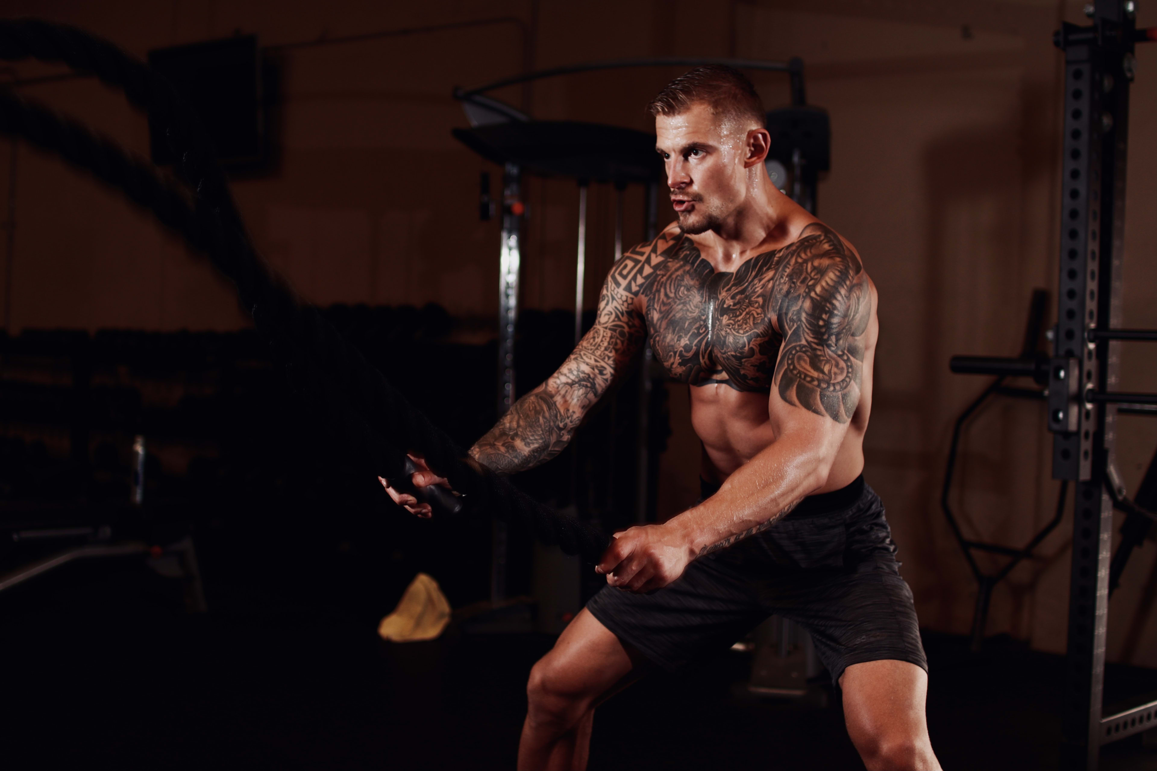 Ein Mann mit einer Tätowierung auf dem Arm posiert für ein Fitness-Fotoshooting.