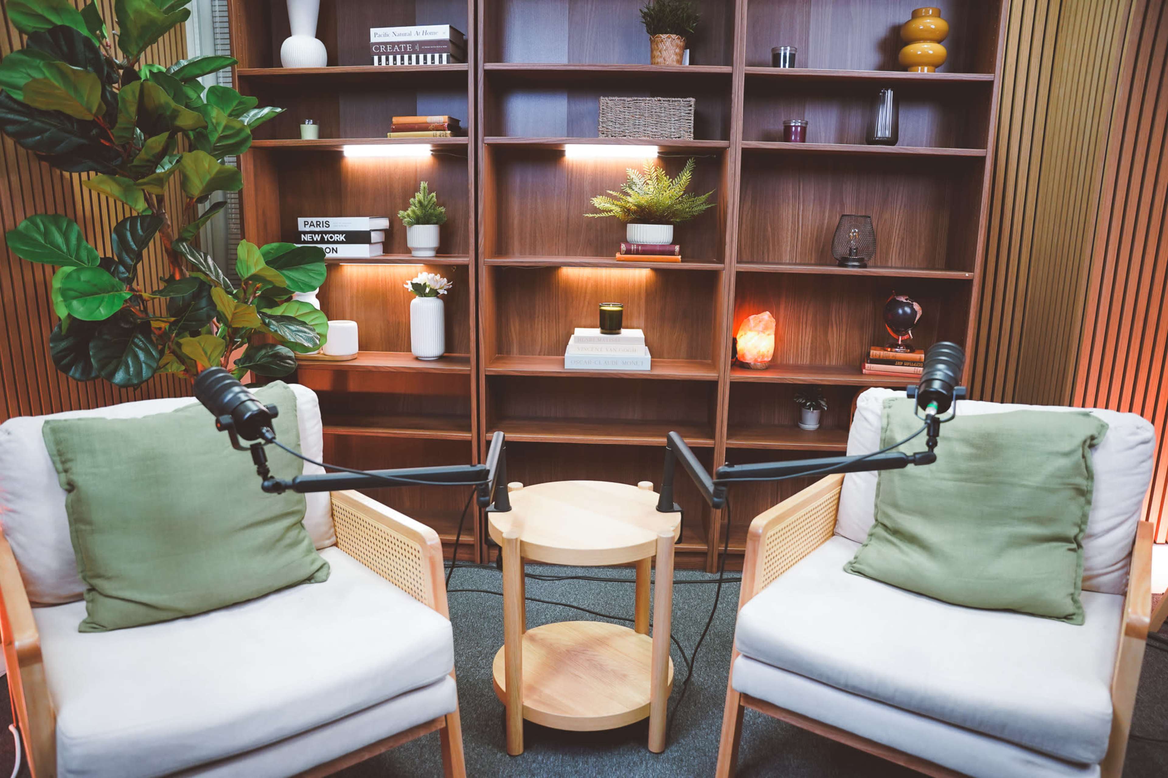 The image shows a modern seating area with two chairs and a small table, set against a wooden shelf displaying various decorative items and plants.
