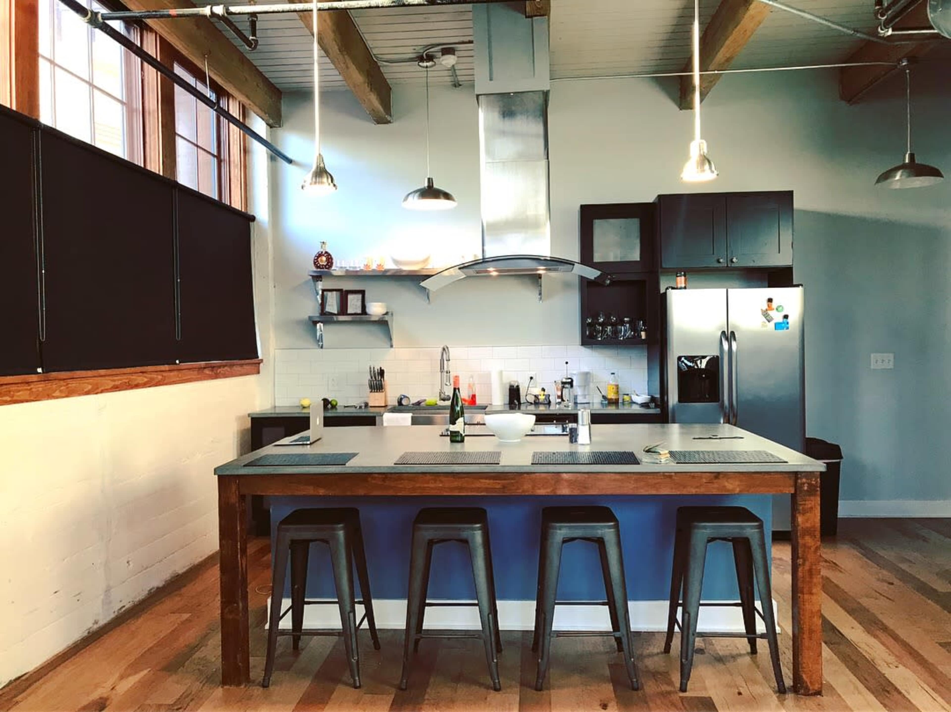 A modern kitchen with a large central island, bar stools, and stainless steel appliances.