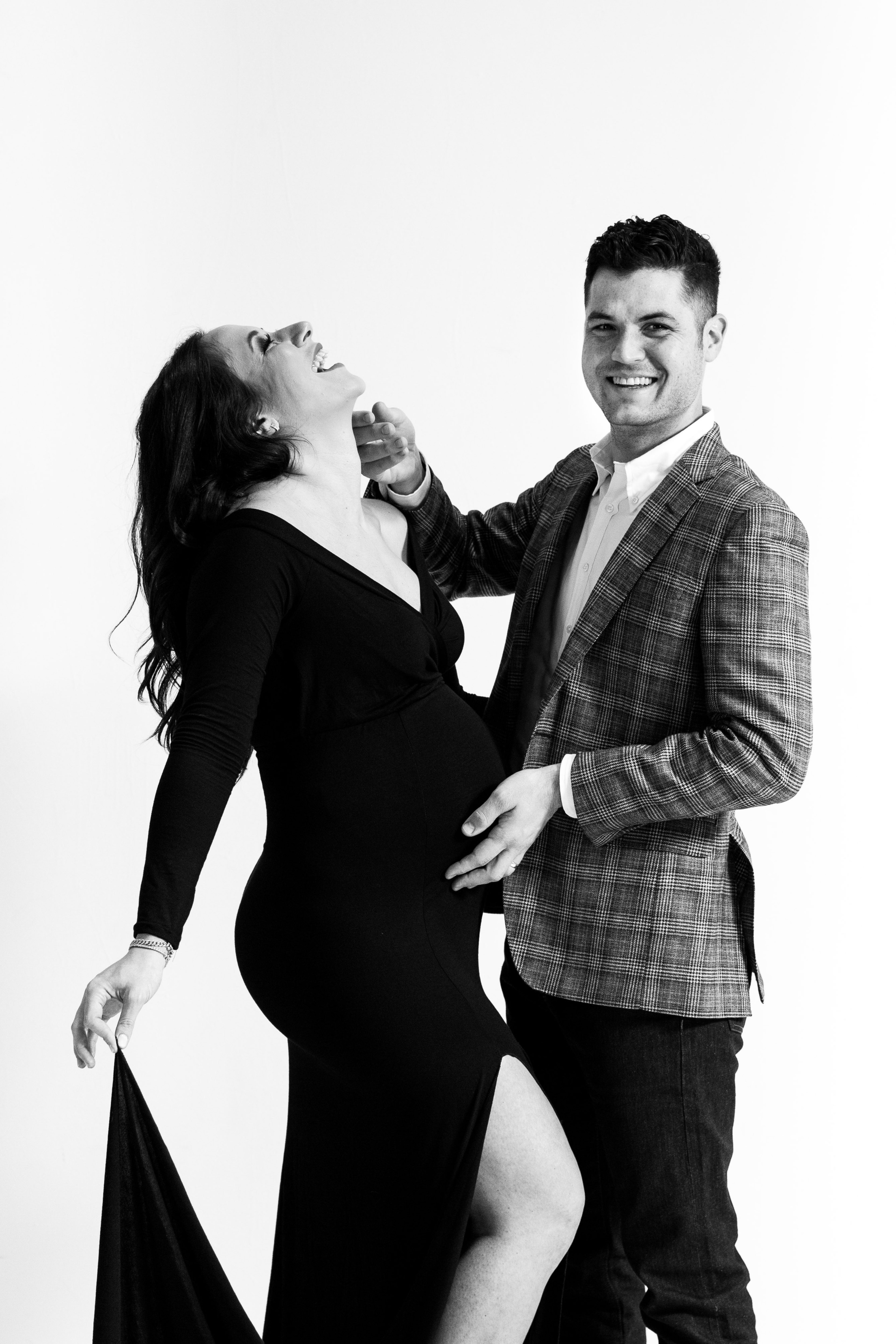 A black maternity photo shoot with a pregnant woman in a dress and a man in a suit.