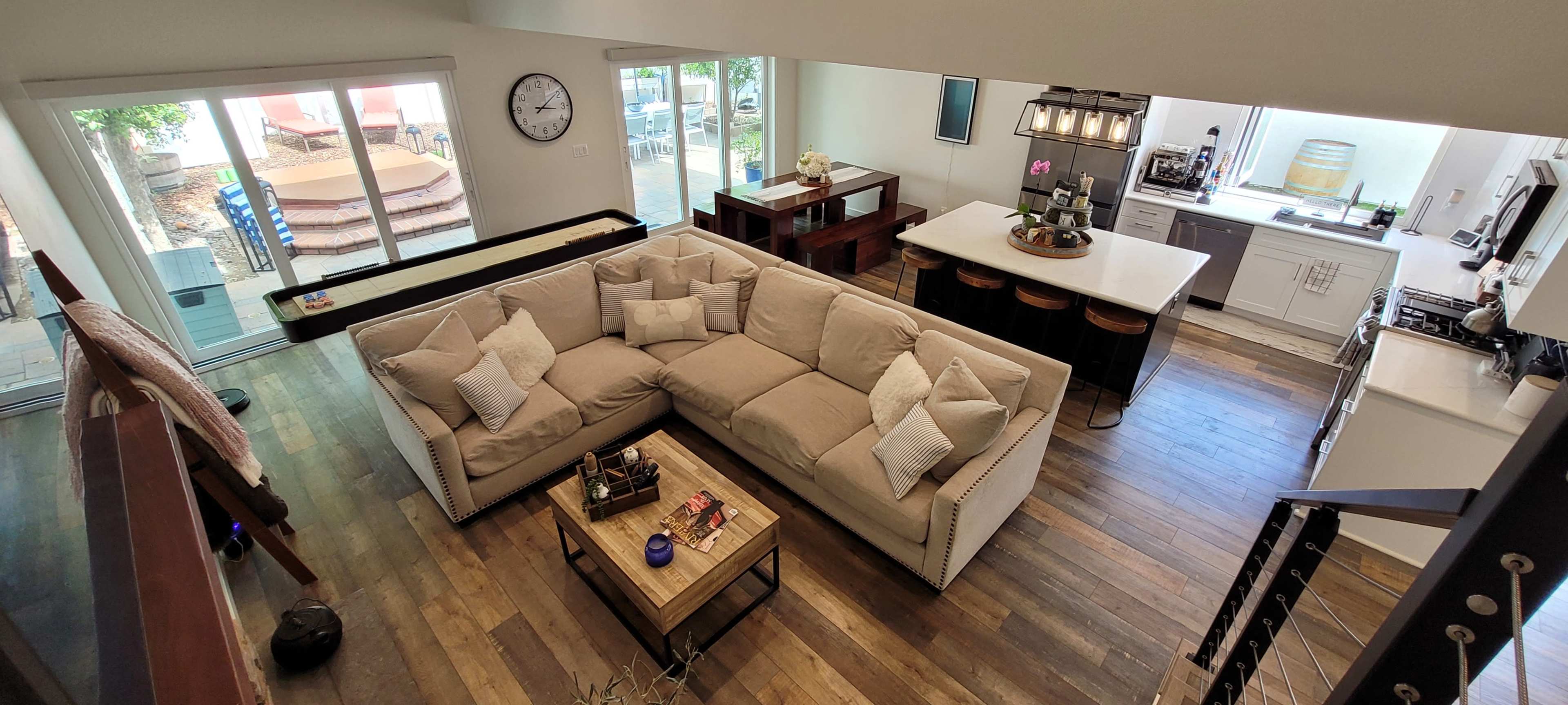 The image shows a spacious living area featuring a large sectional sofa, a coffee table, and an open kitchen with a dining area.