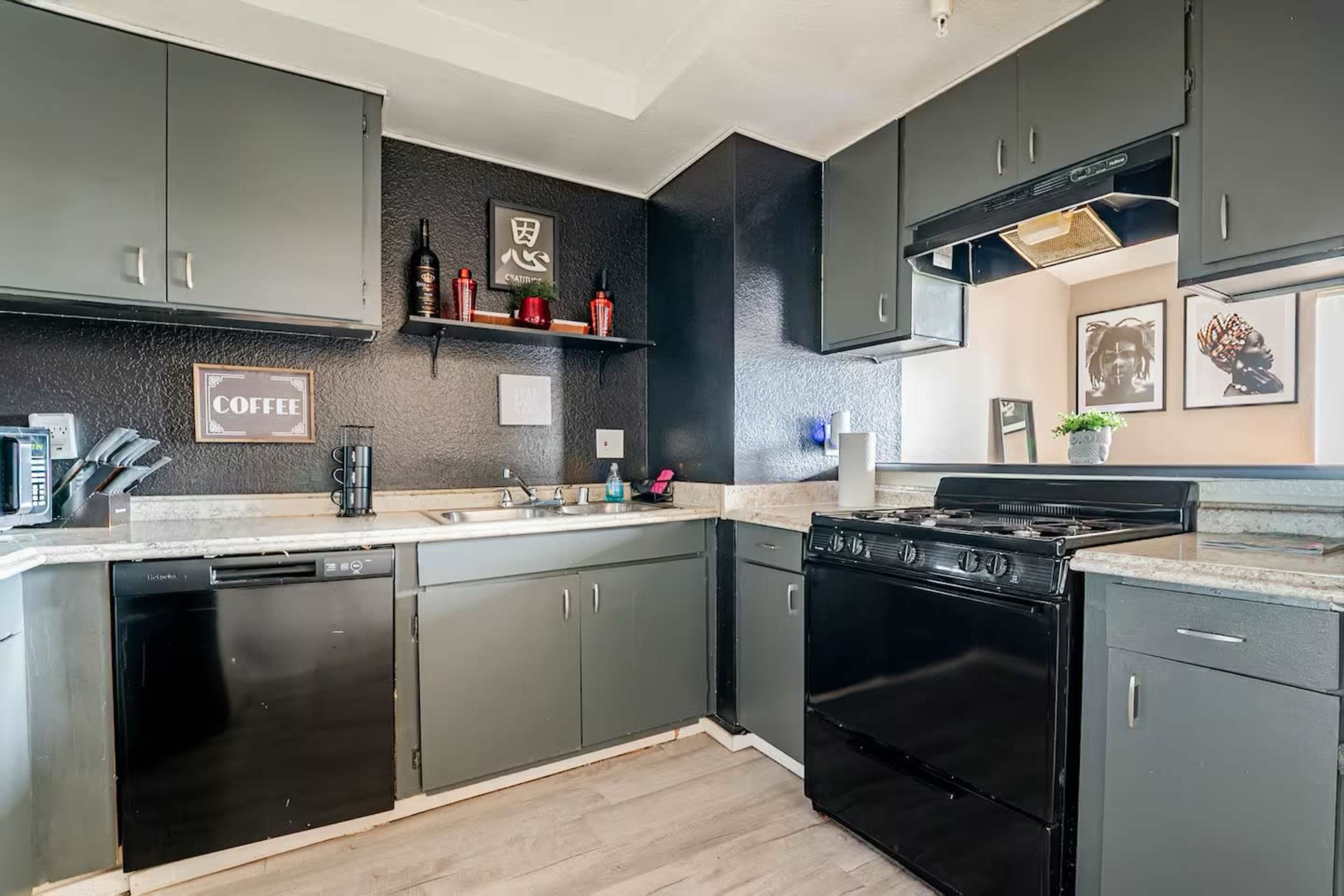 The image shows a modern kitchen with dark cabinets, countertop appliances, and a black stove.