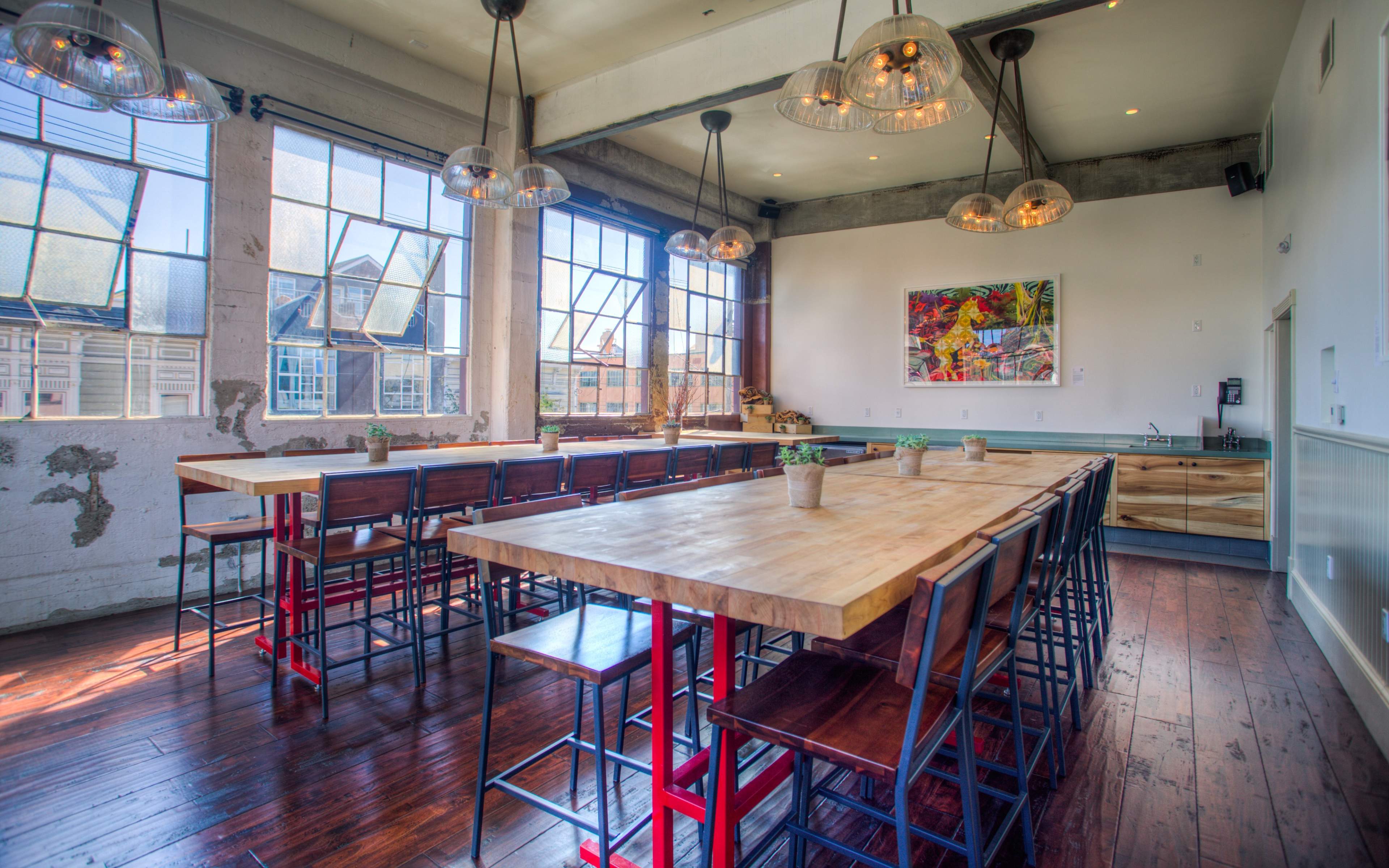 The image shows a spacious dining area with large windows, wooden tables, and metal chairs.