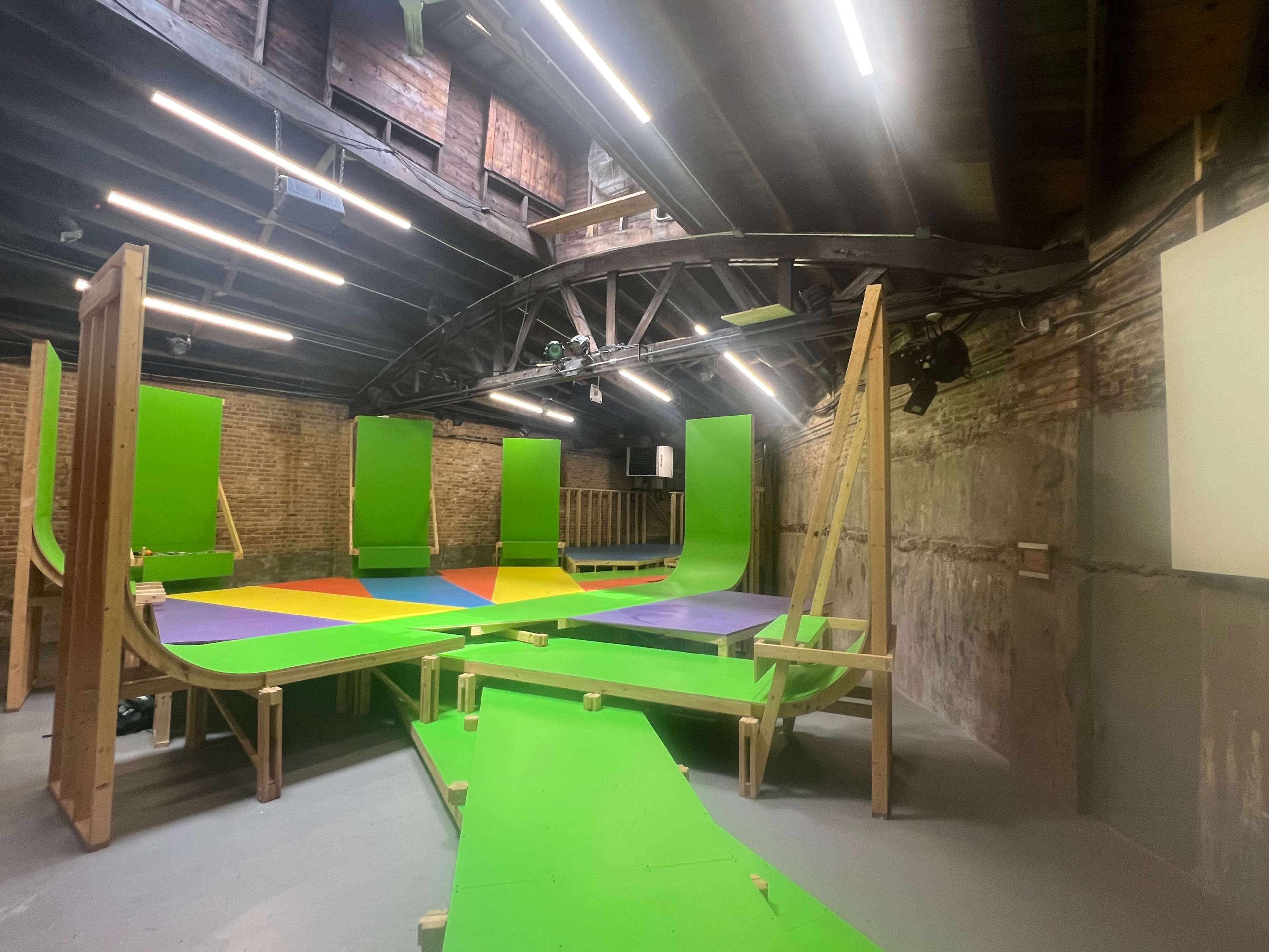 The image shows an indoor skate park with brightly colored ramps and surfaces arranged in a geometric layout.