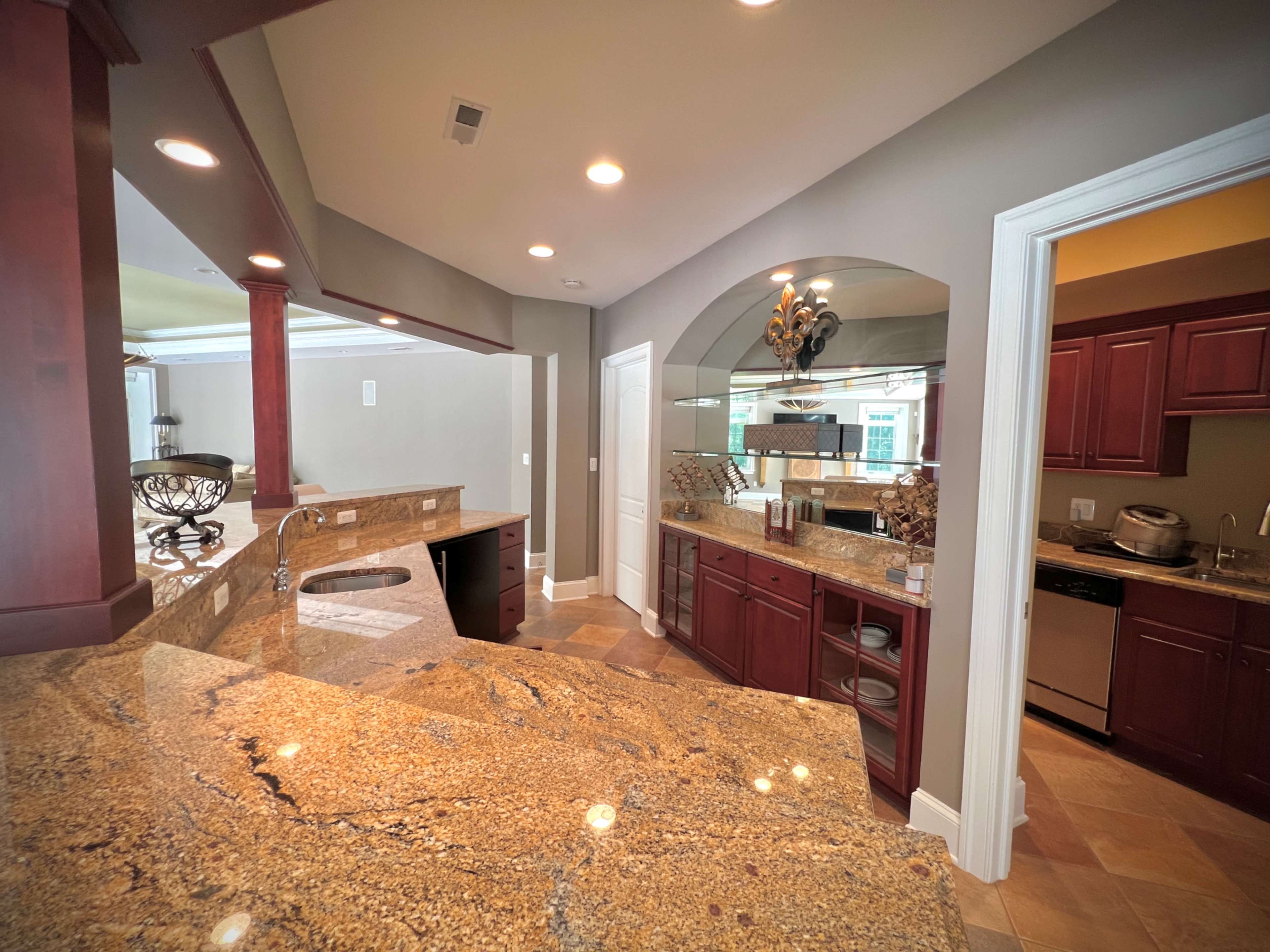 The image shows a modern kitchen with wooden cabinetry, granite countertops, and stainless steel appliances.