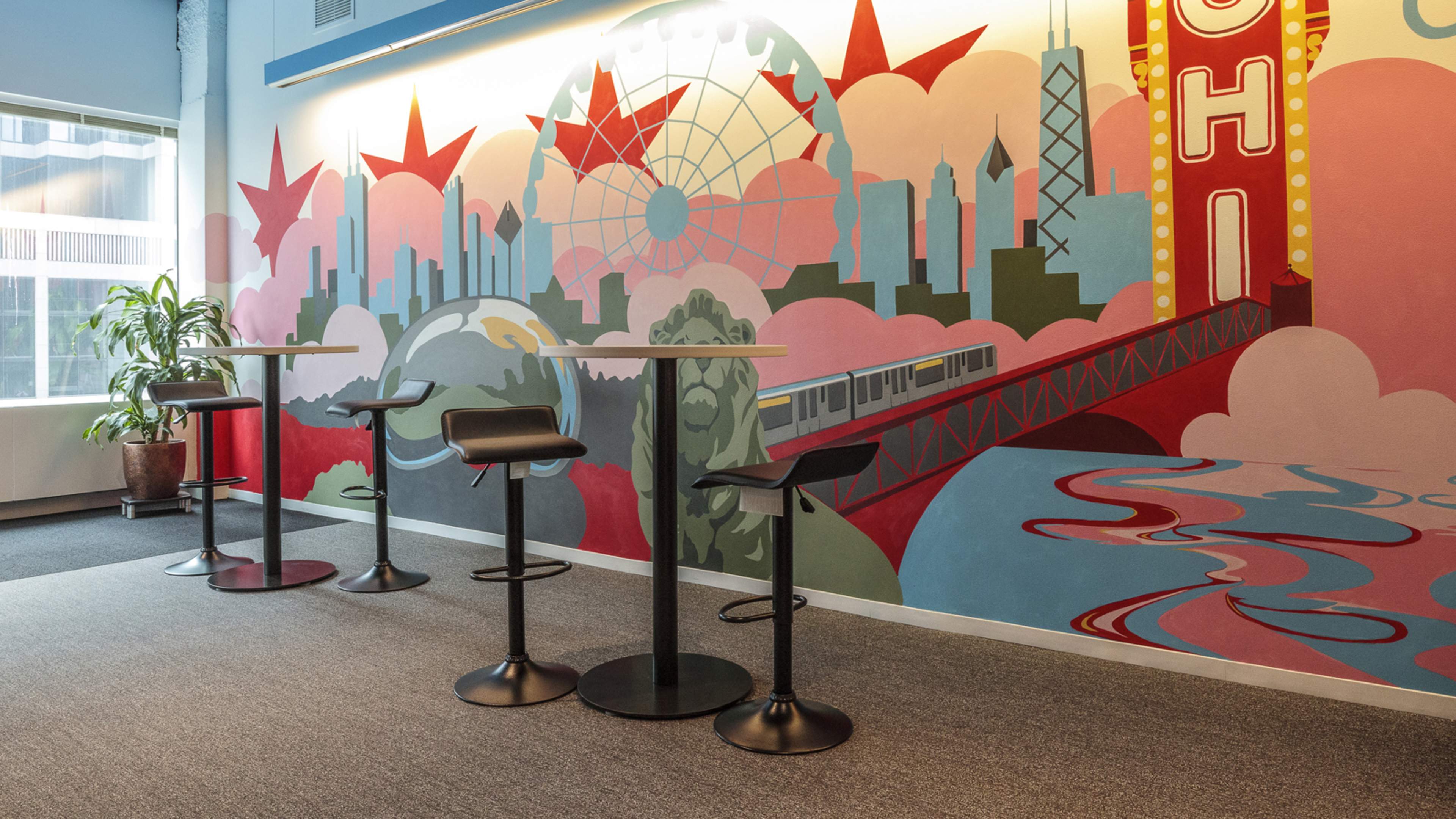 A modern seating area with four high stools arranged in front of a colorful mural depicting an urban landscape.
