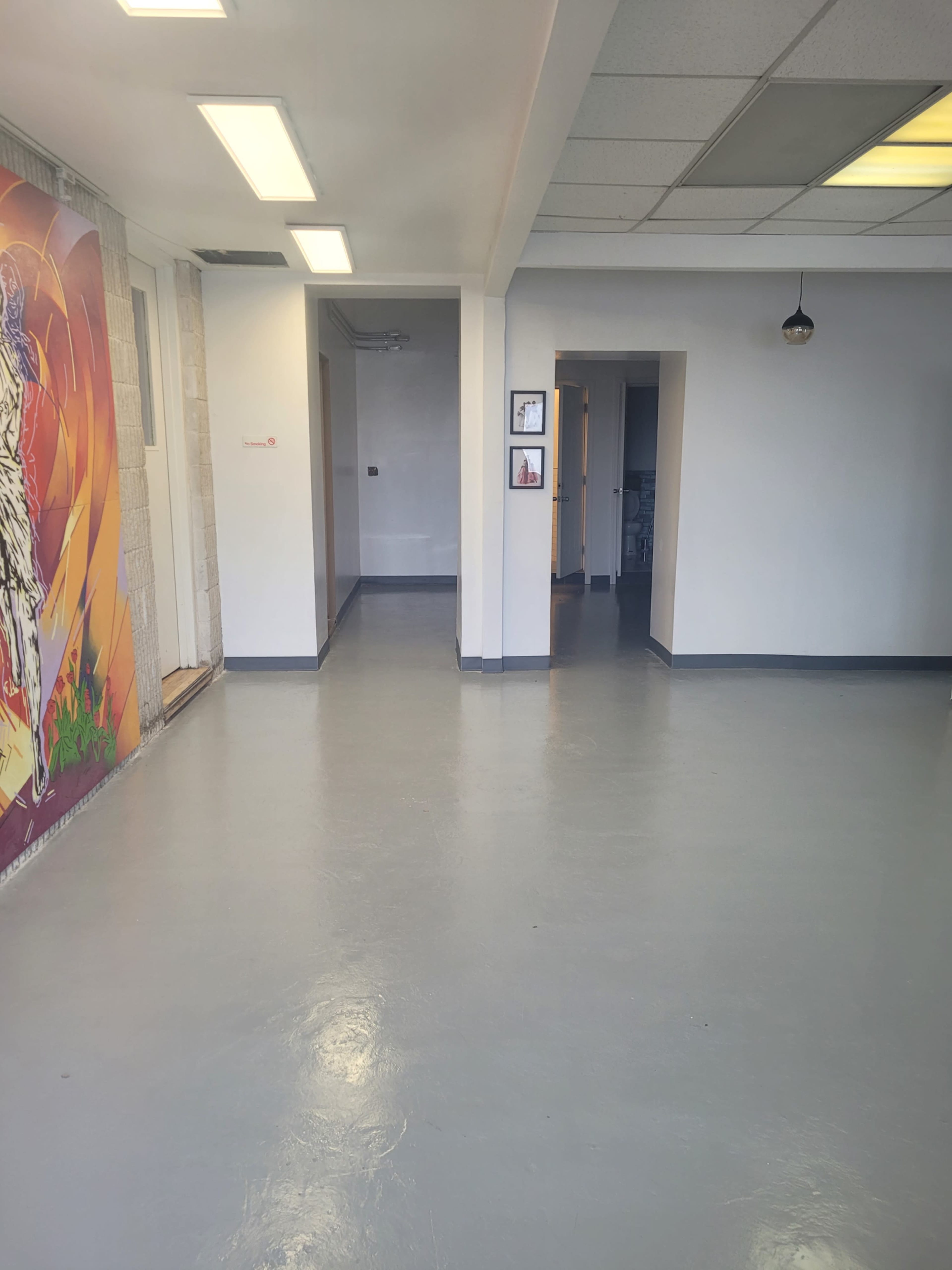 The image shows a spacious, well-lit interior with a gray floor and a painted mural on the left wall.