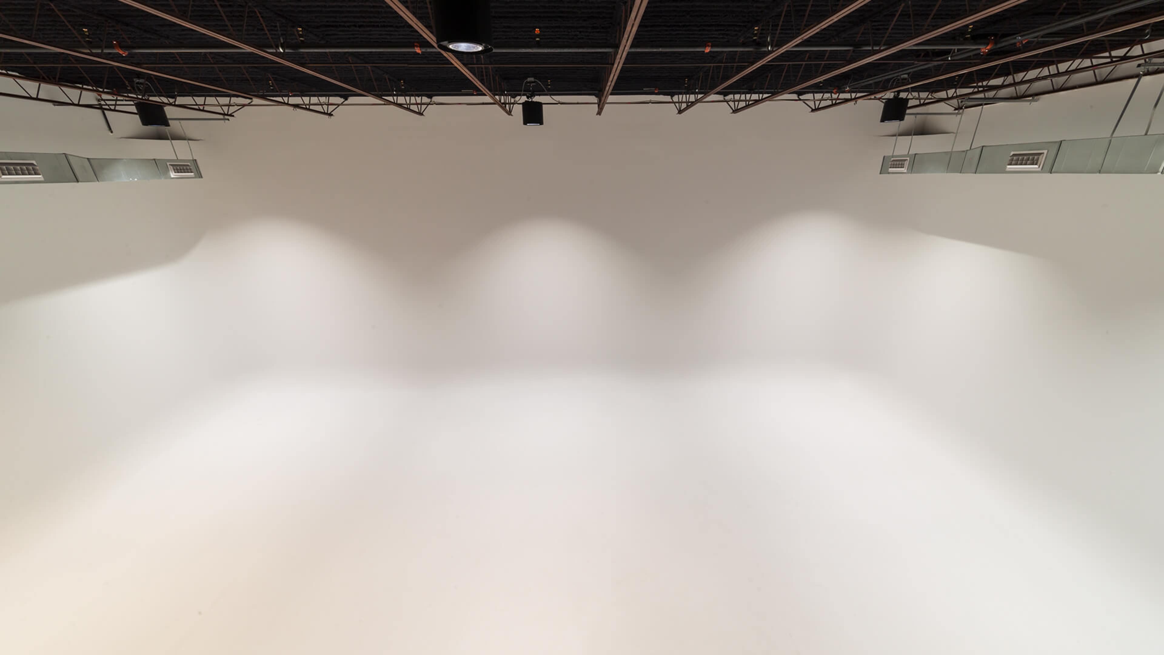 A large, empty white studio space with overhead lighting.