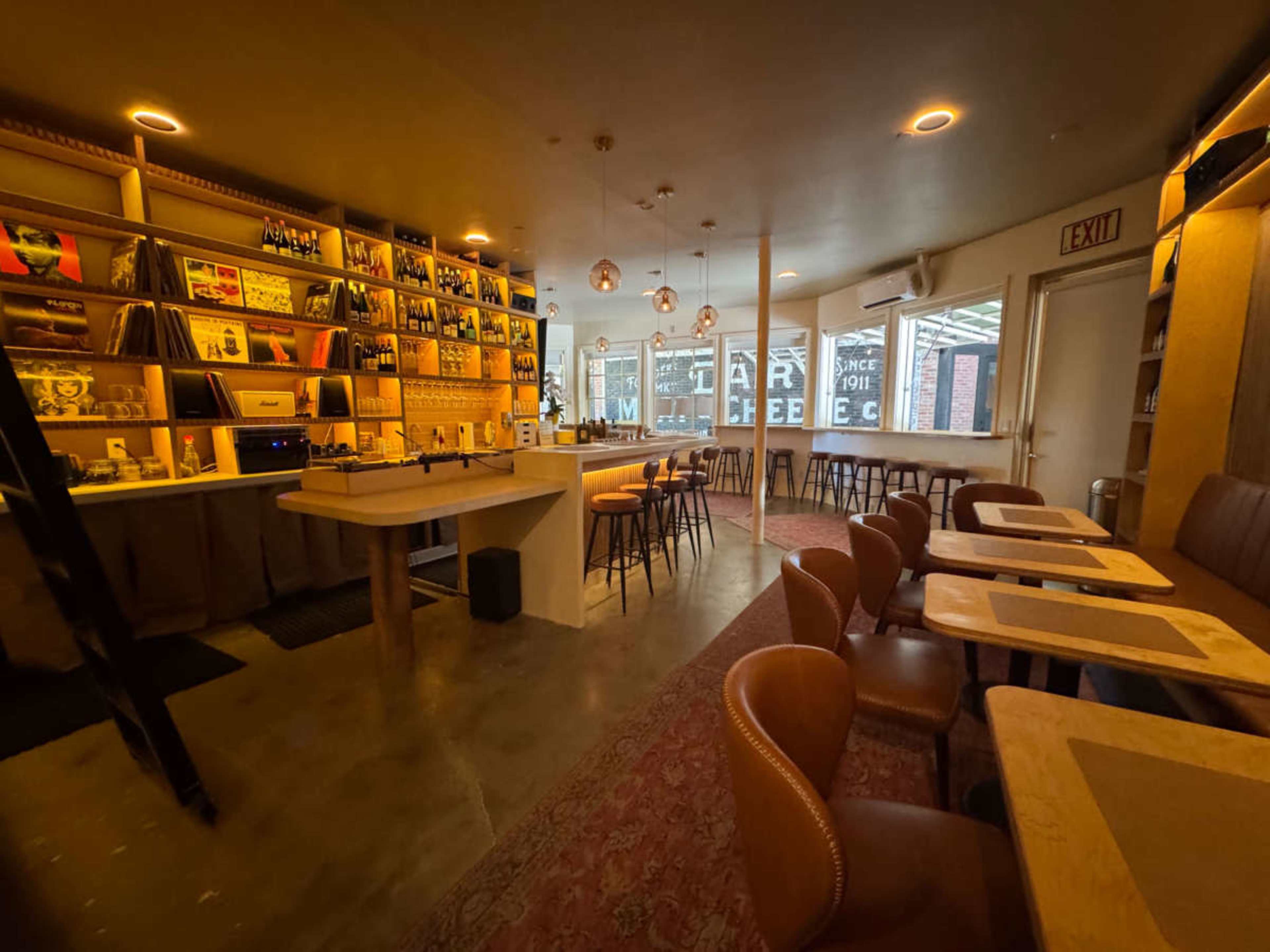 The image shows a modern café interior with a long counter, shelves filled with books and decor, and tables arranged for customers.