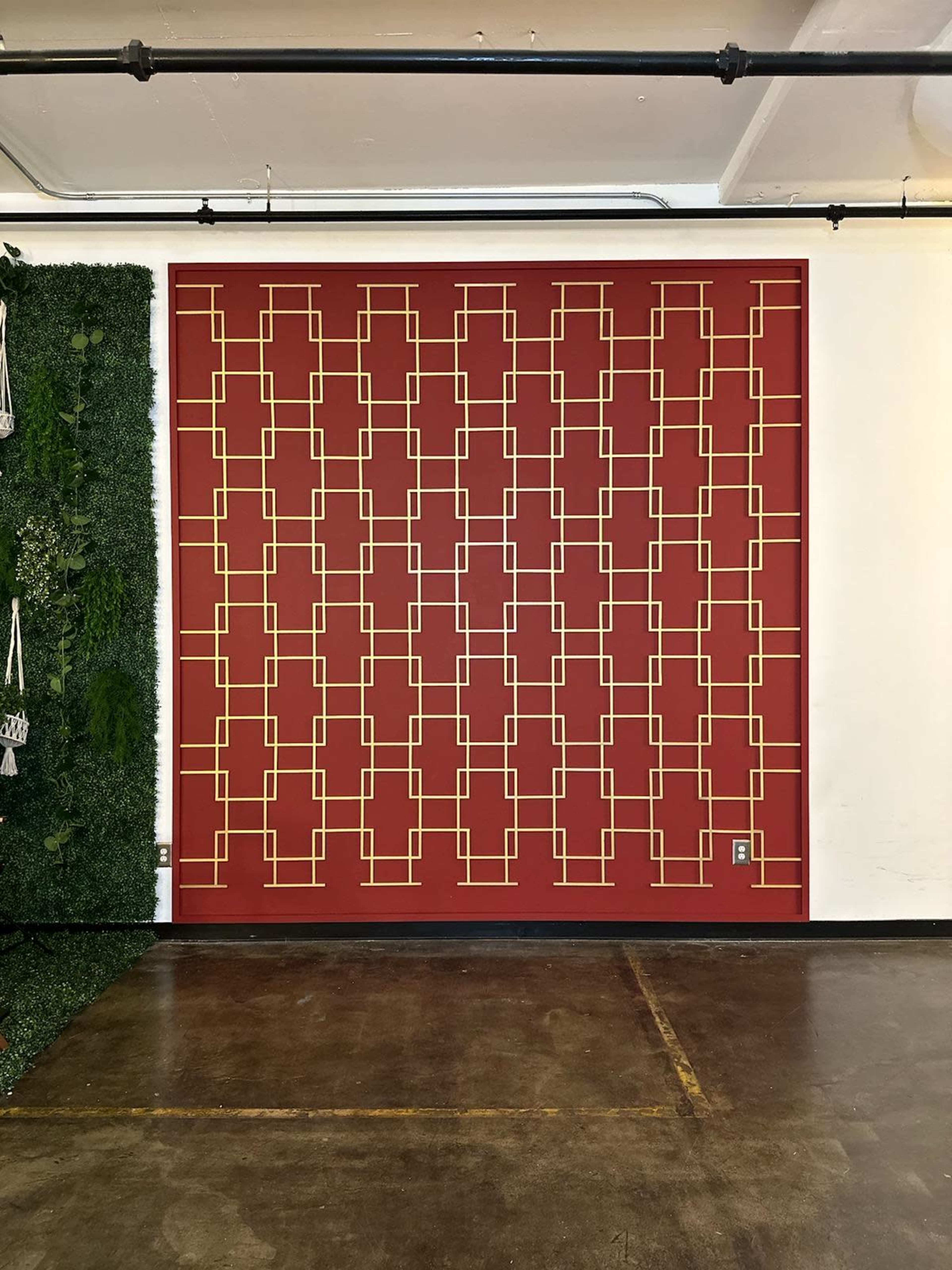 A red wall featuring a geometric pattern of golden rectangles arranged in a grid.