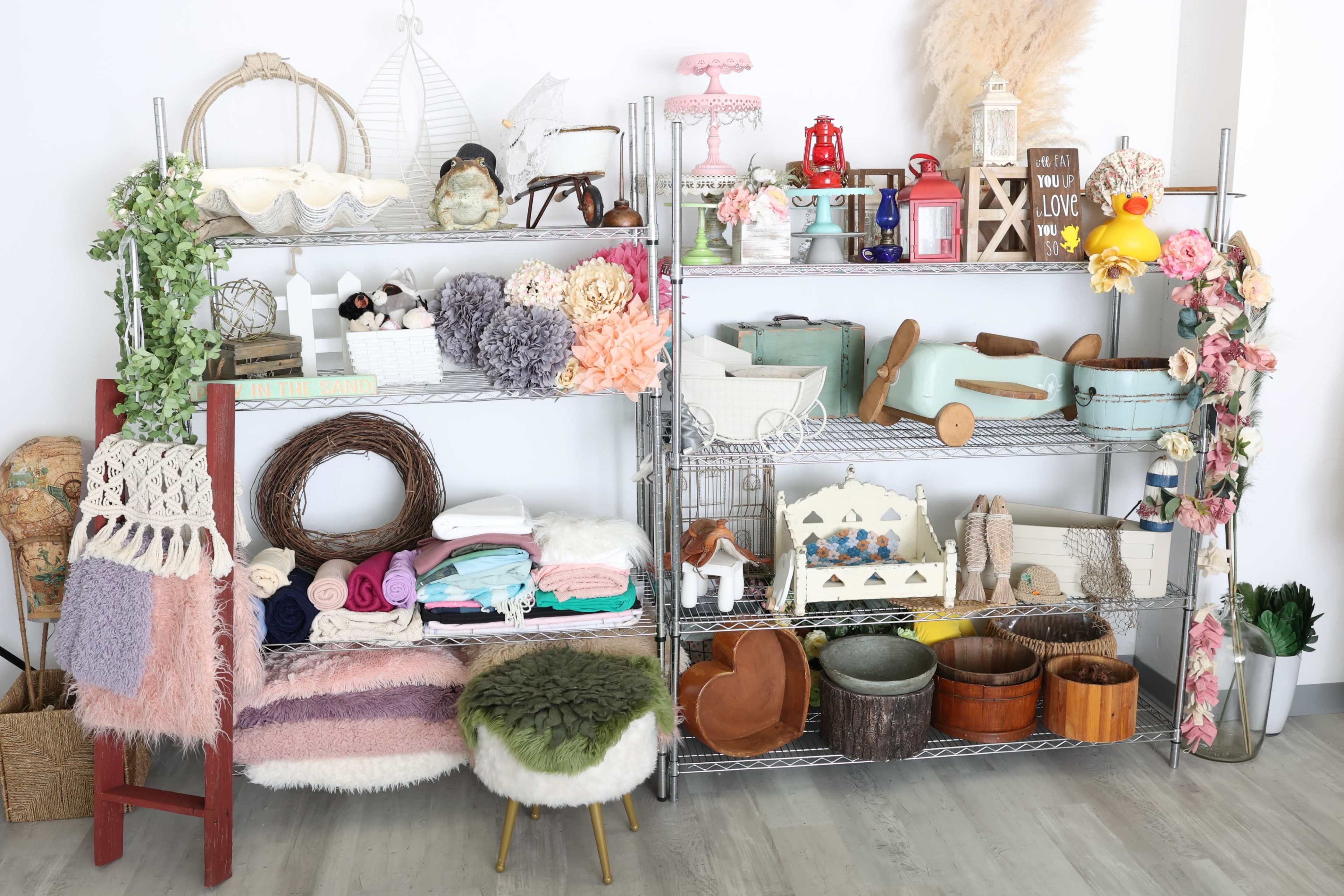 A display of various decorative items and craft supplies organized on metal shelving units, including baskets, fabric rolls, and vintage-style decor.