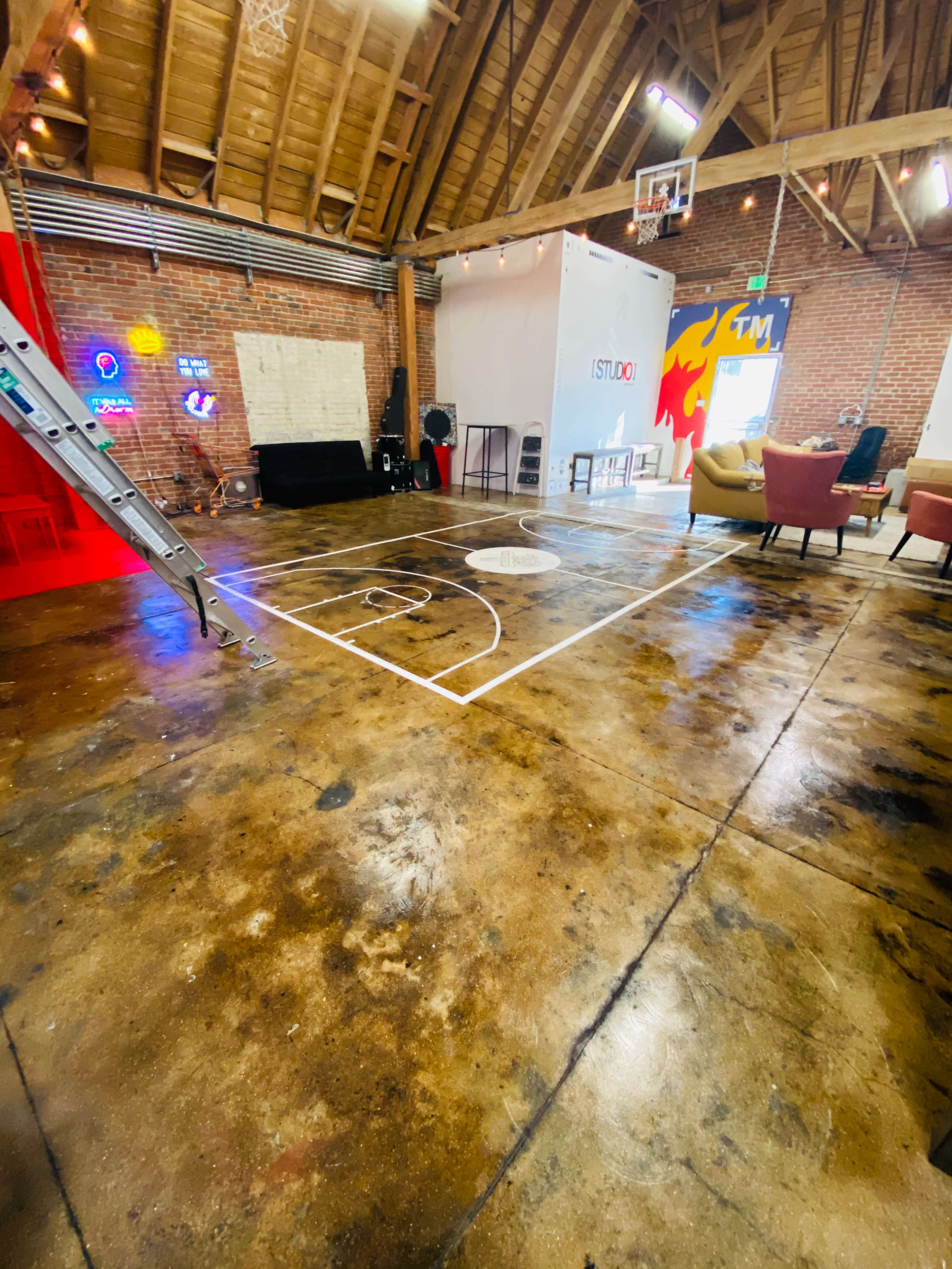 A spacious room with a marked basketball court on the floor, surrounded by brick walls and modern seating arrangements.