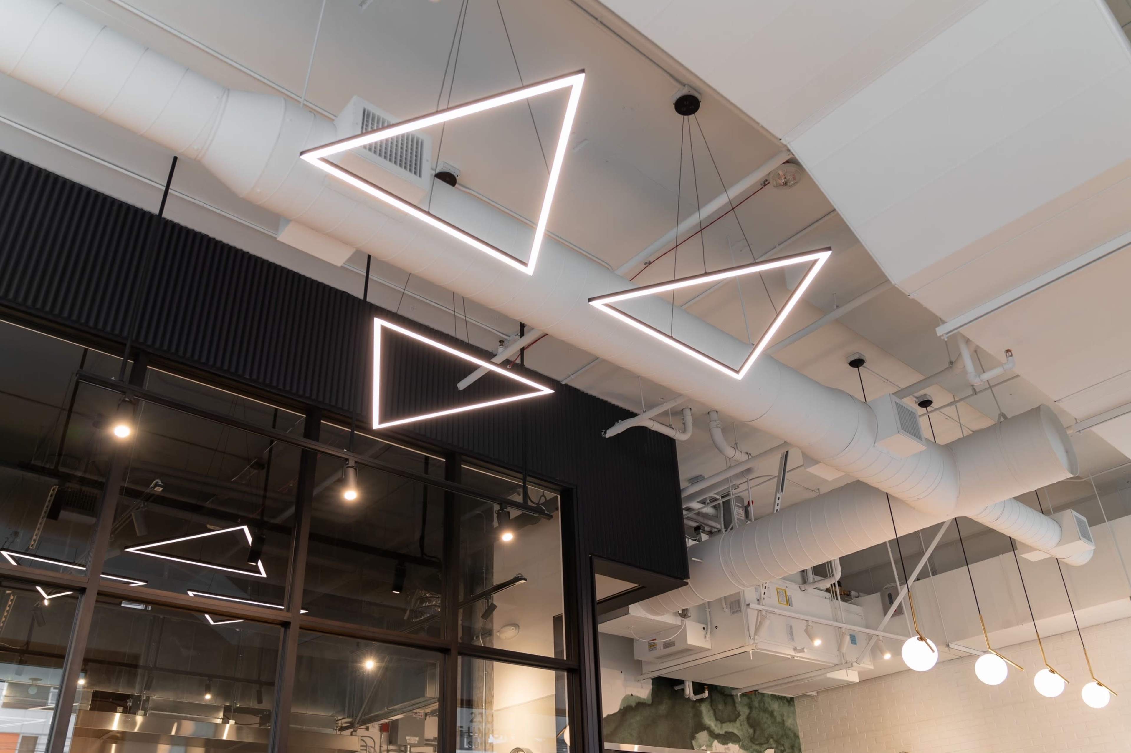 Geometric LED pendant lights suspended from a ceiling in a modern interior space.
