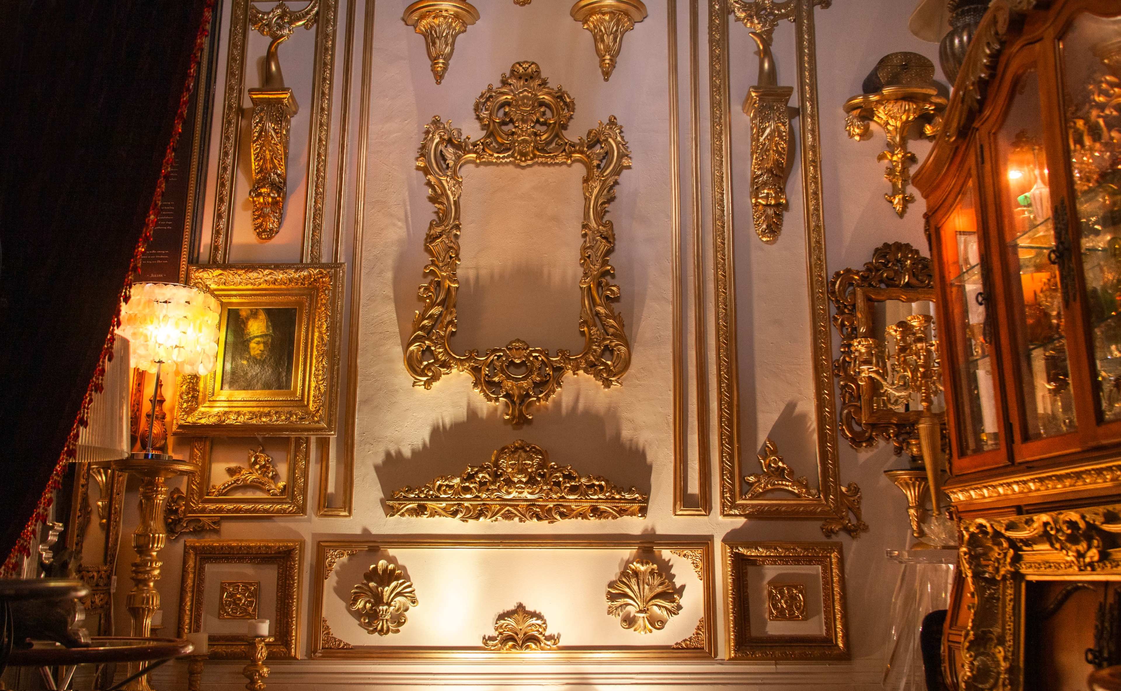 The image features an ornate interior wall adorned with intricate gold decorations, frames, and a glass display cabinet.