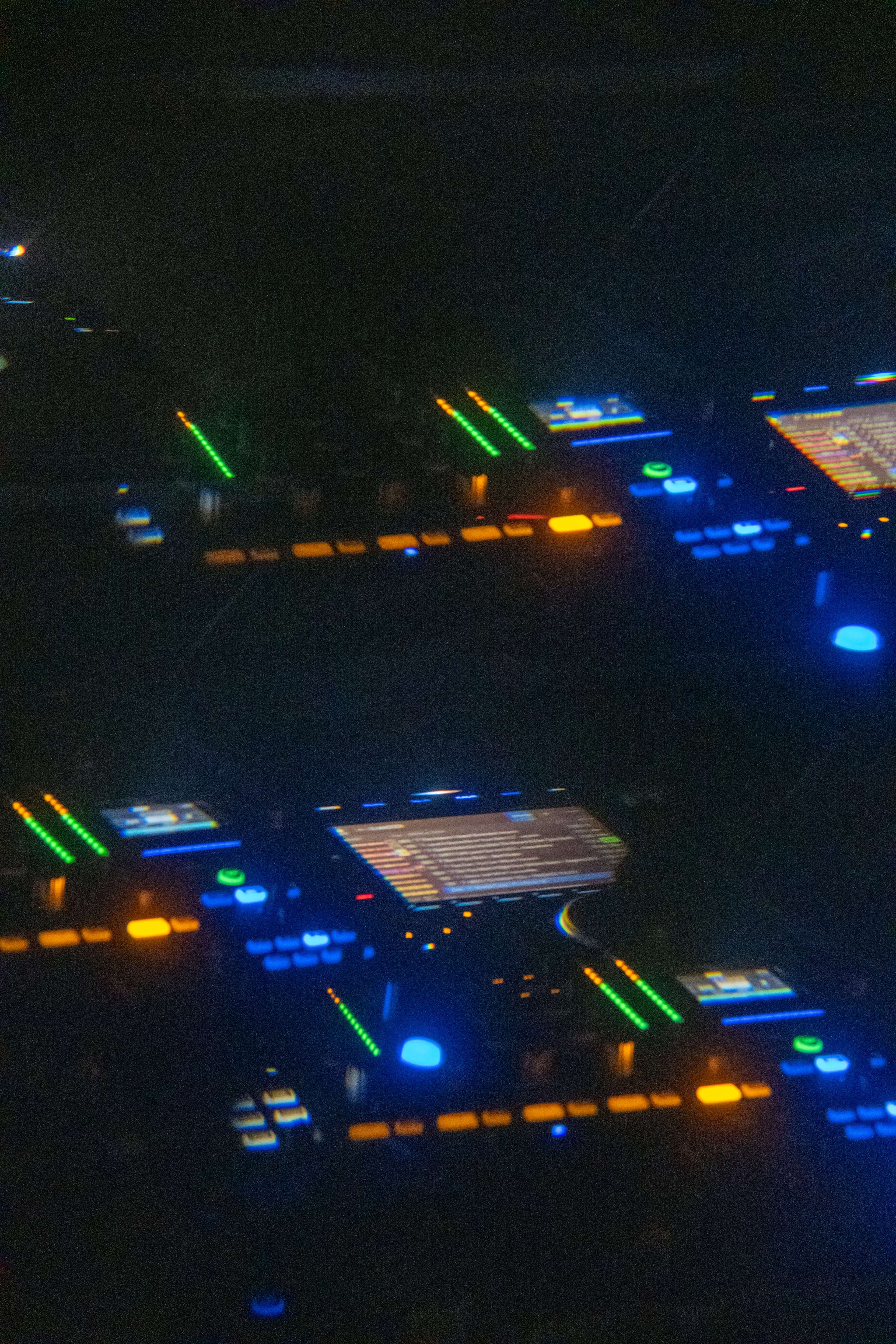 The image shows a close-up view of a professional DJ setup with illuminated buttons and sliders.