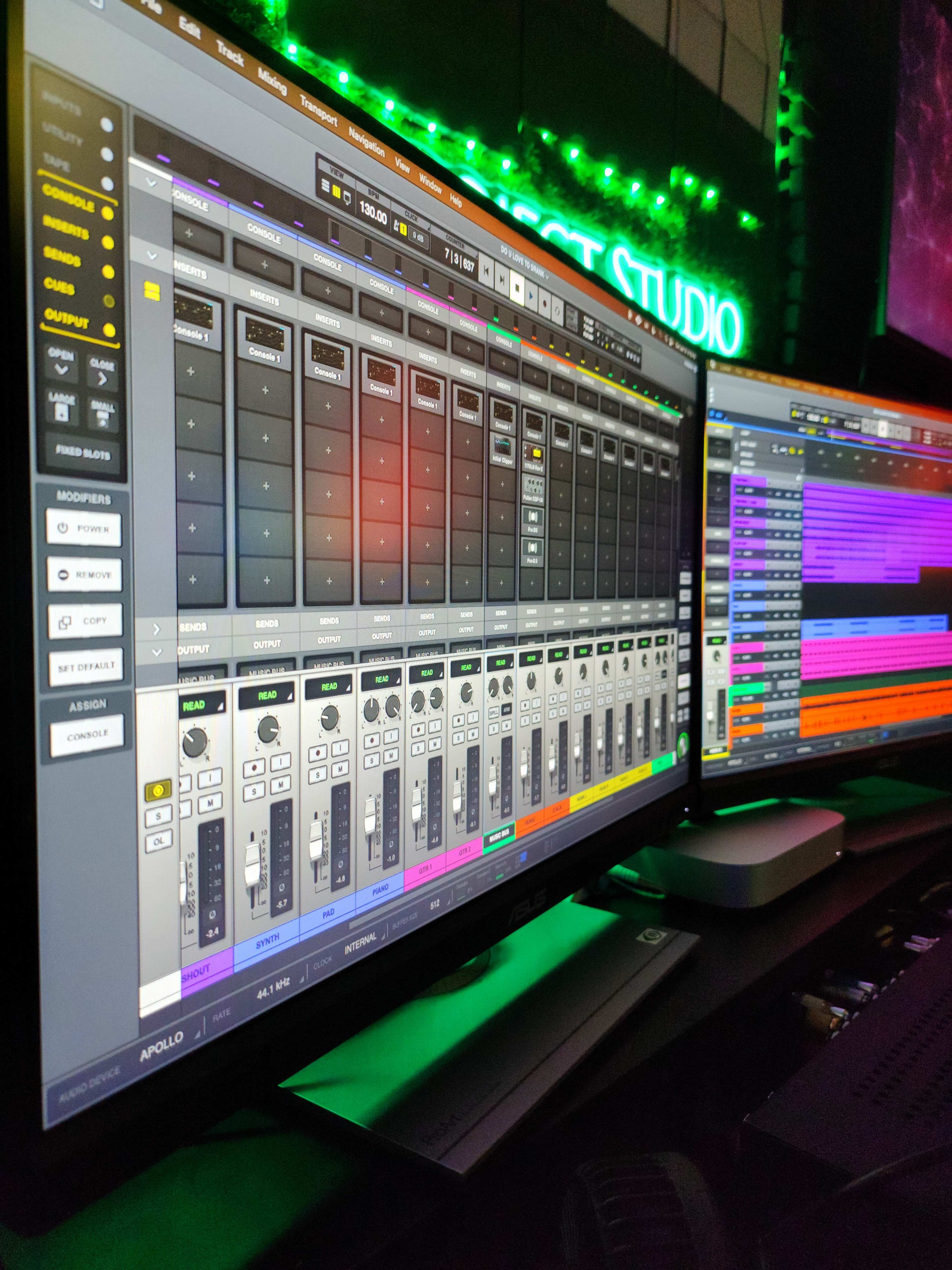 The image shows a digital audio workstation on two monitors, displaying various sound mixing controls and a vibrant color-coded track layout.