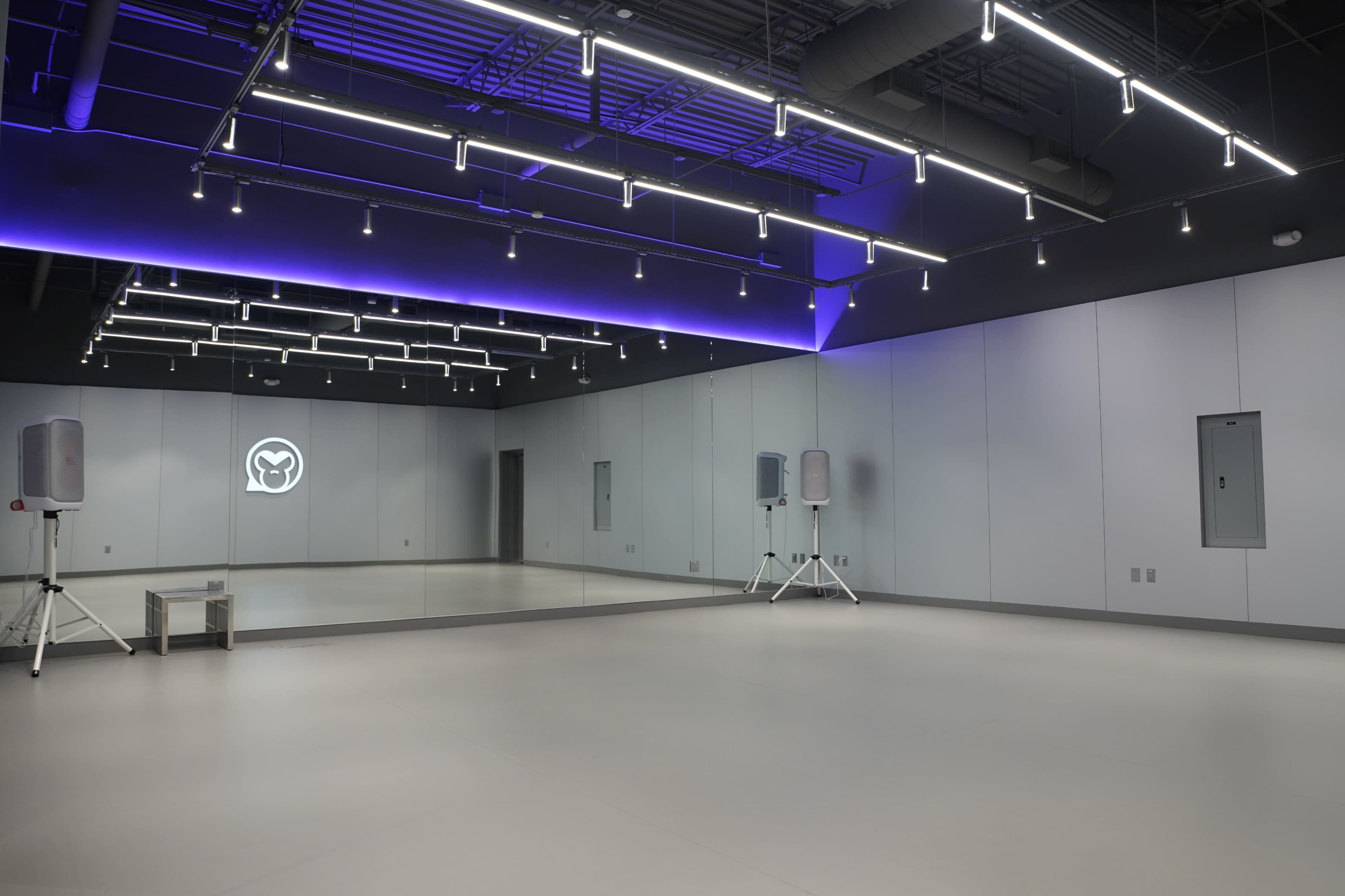 The image shows a spacious, modern dance studio with a large mirror on one wall and ambient lighting.