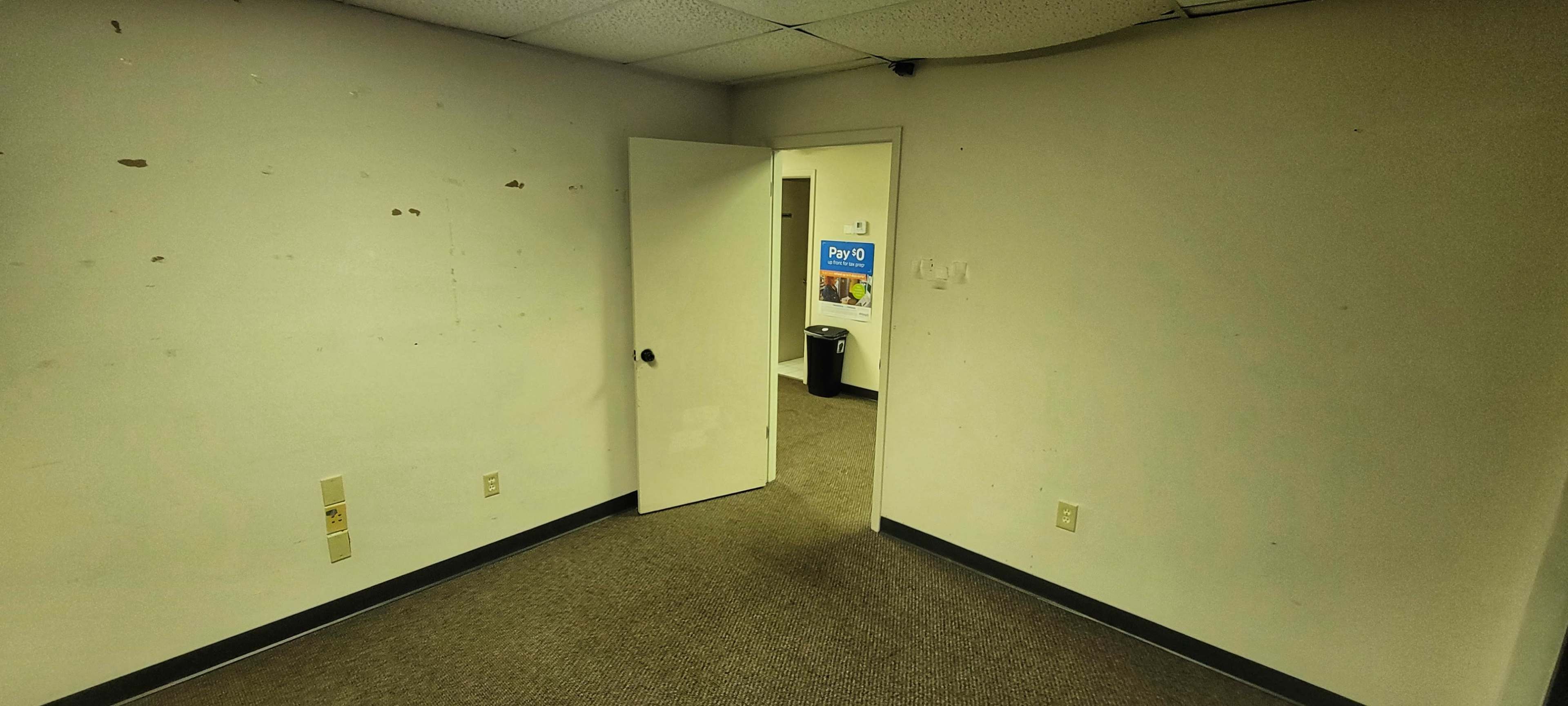 The image shows a bare, empty room with a partially open door leading to another area.