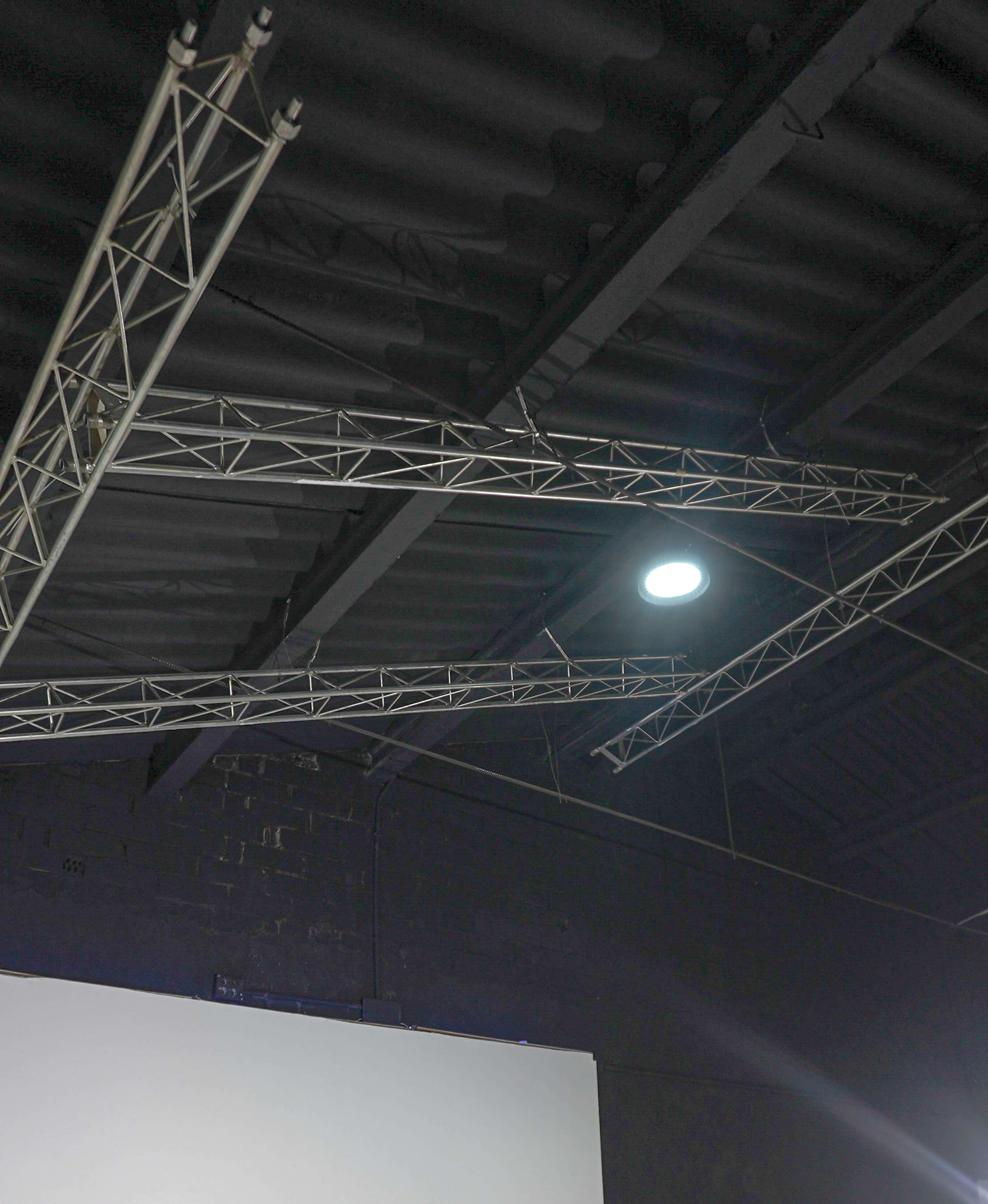 The image shows metal trusses and overhead lighting fixtures within an industrial space.