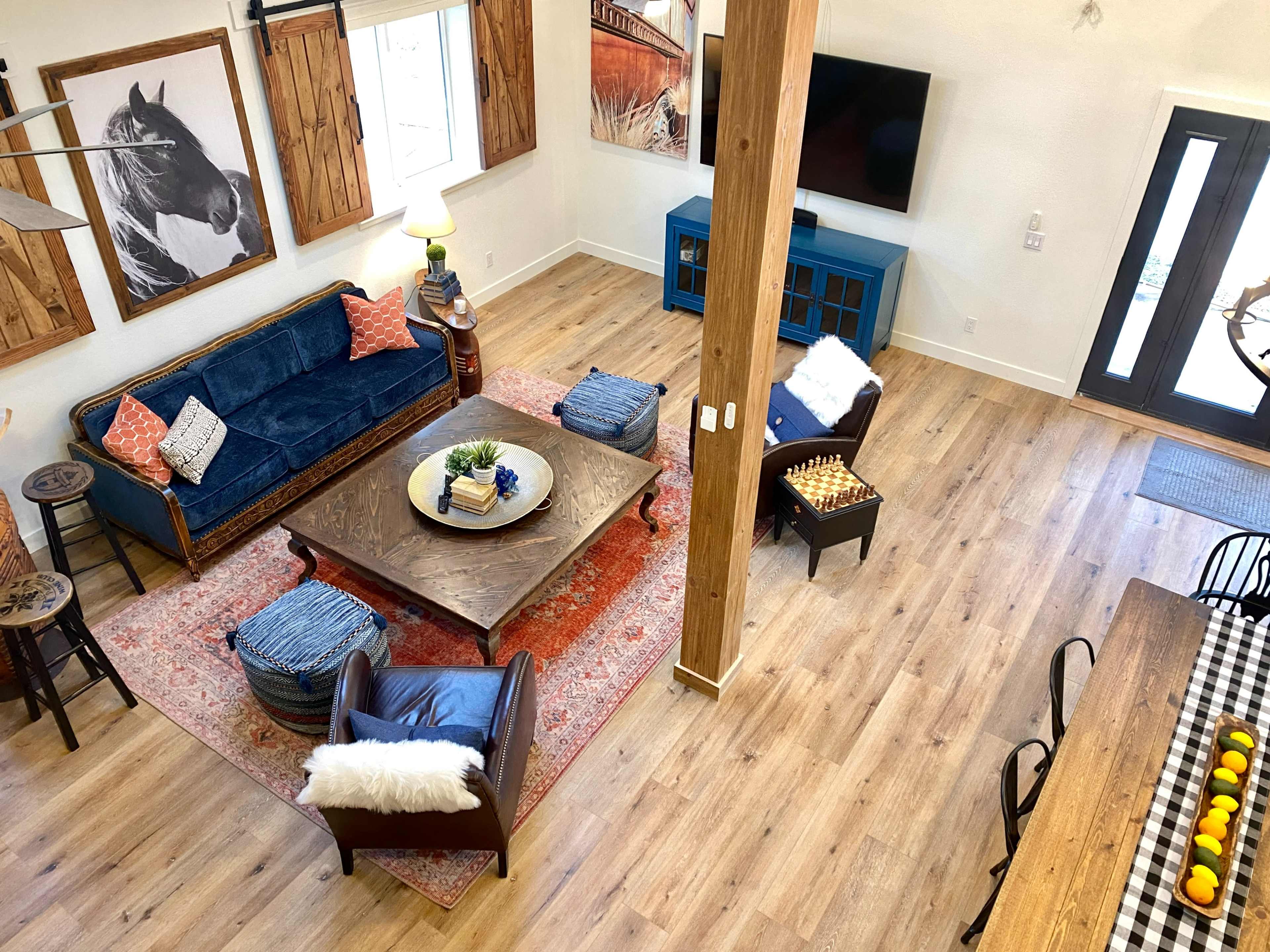 A spacious living area with a blue sofa, a large coffee table, and a dining table, all surrounded by wooden accents and decorative artwork.