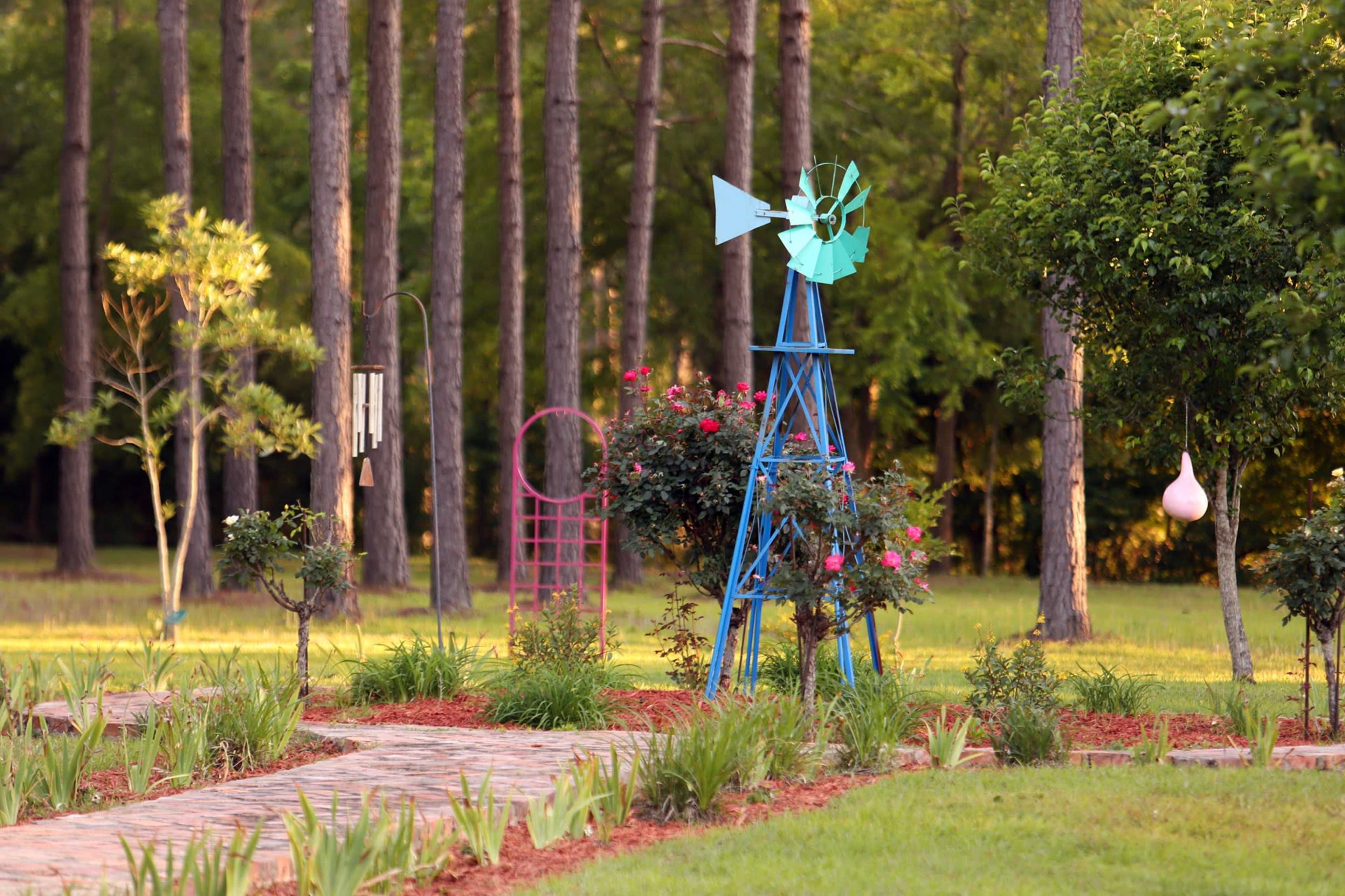 A colorful windmill stands in a garden surrounded by pathways and trees.