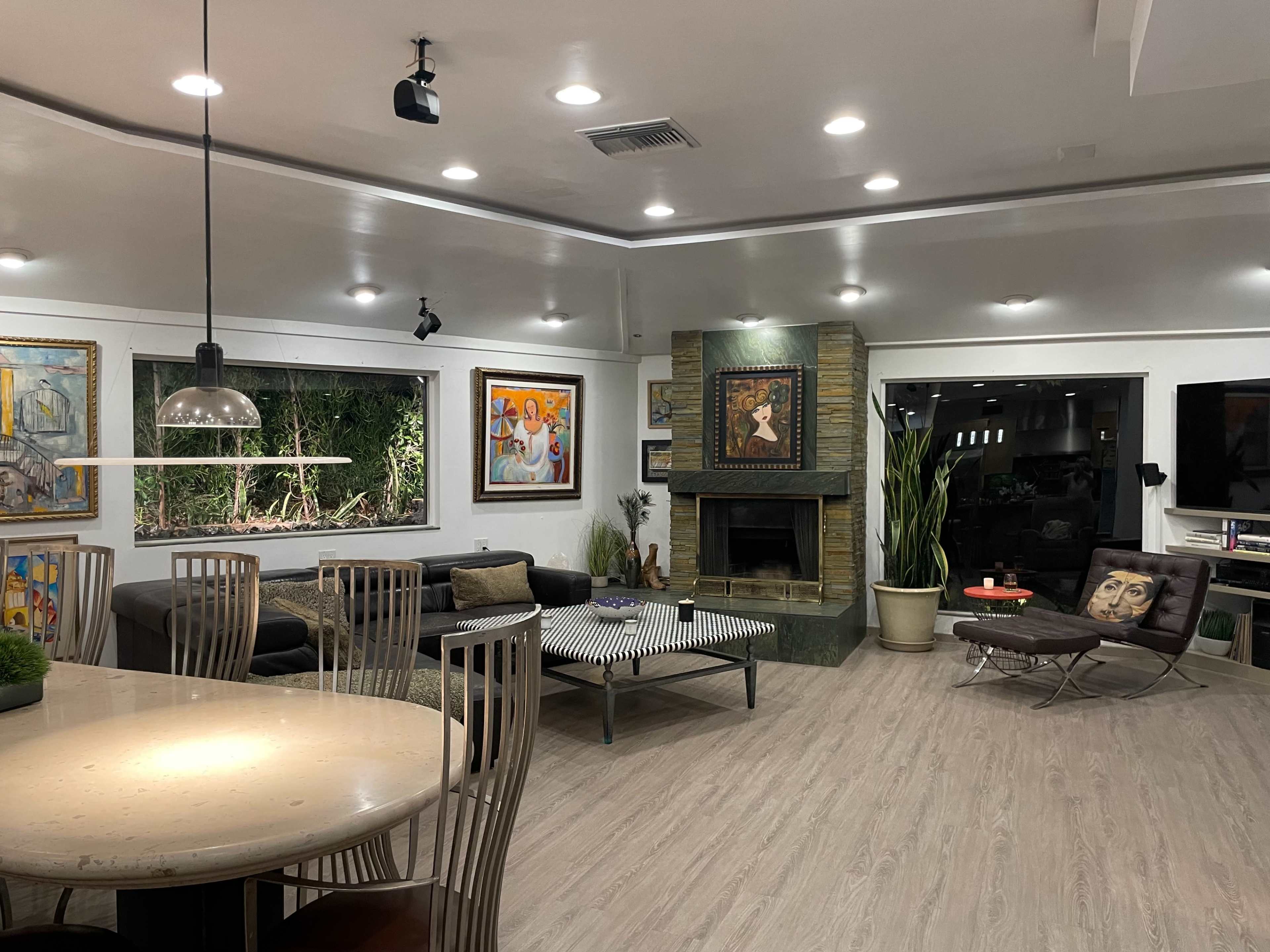 A modern living room with artwork on the walls, a dark sofa, a coffee table, and a stone fireplace.