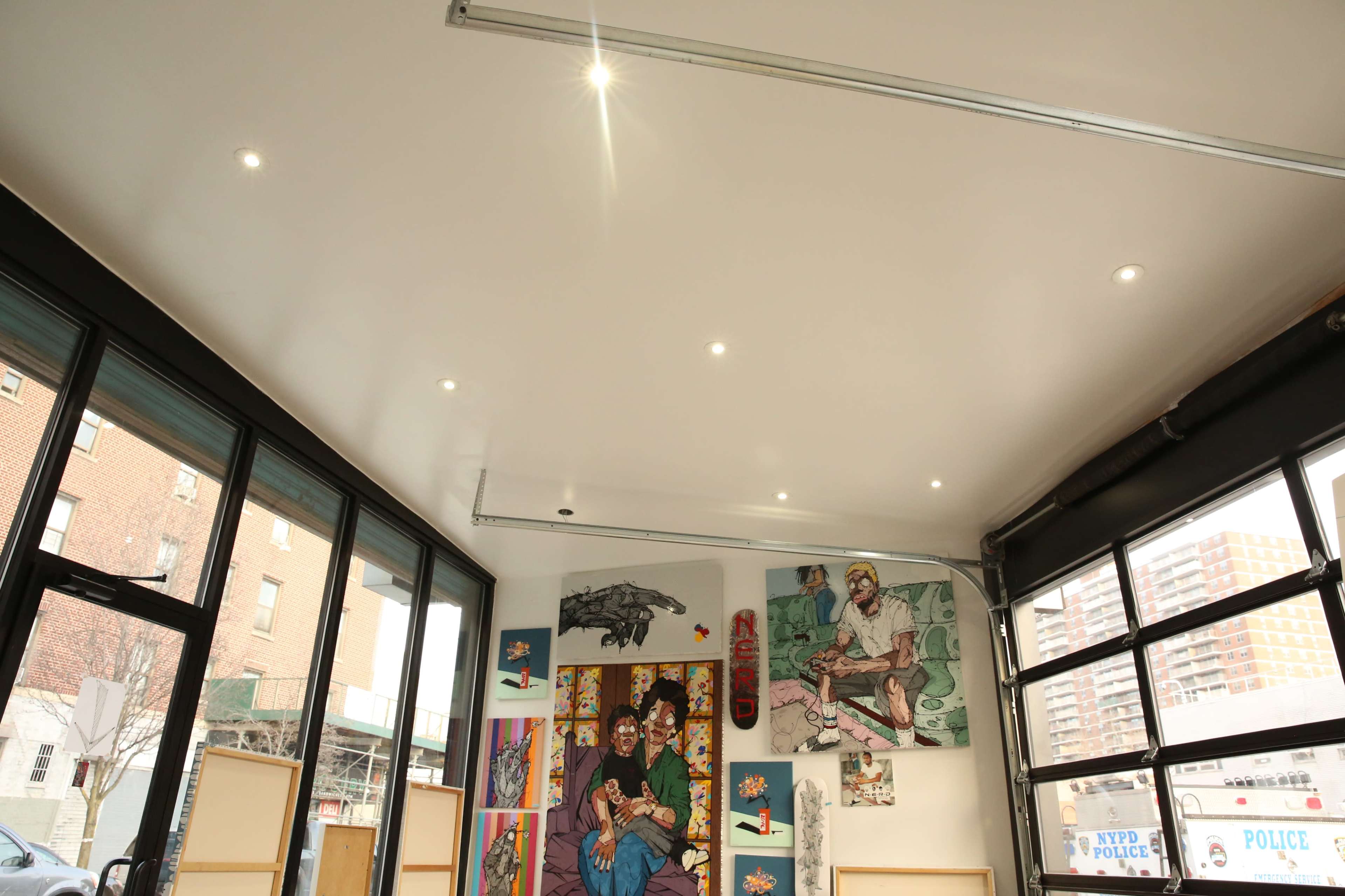 An interior of a modern art gallery with bright ceiling lights and colorful artworks displayed on the walls.