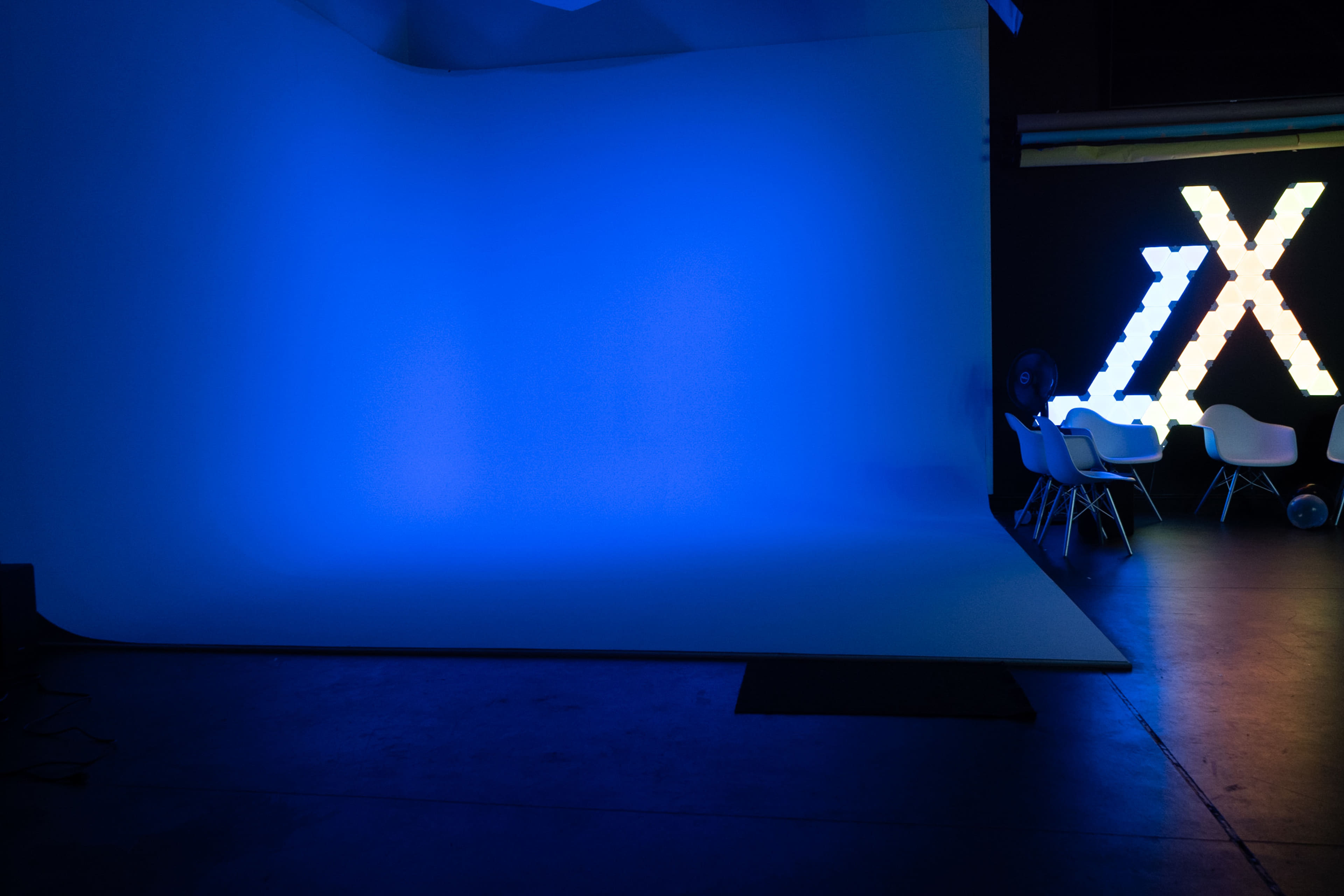 A dimly lit studio with a blue backdrop and illuminated decorative letters on one side.