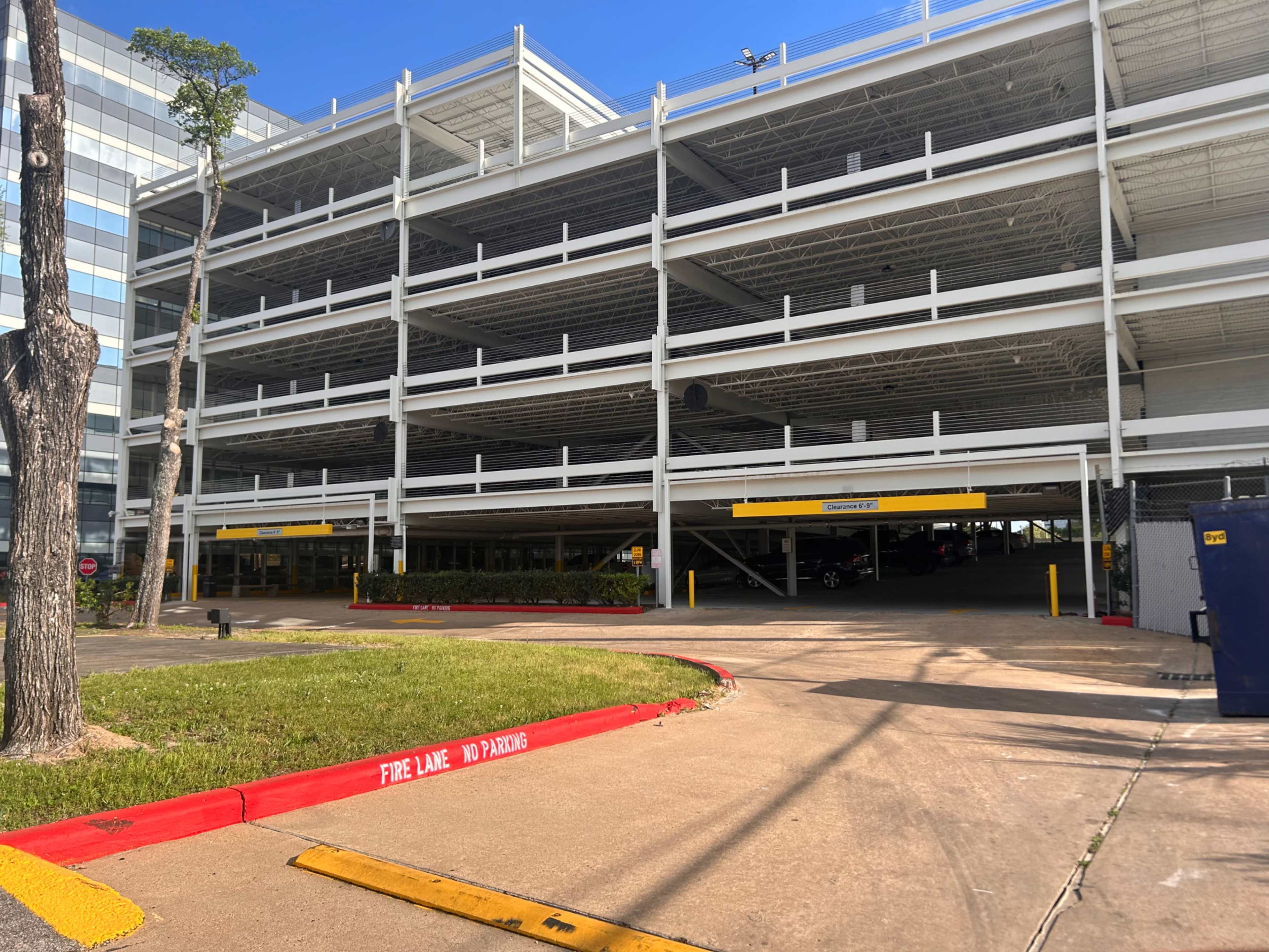 The image shows a multi-level parking garage with a clear path leading to its entrance and marked areas indicating no parking.