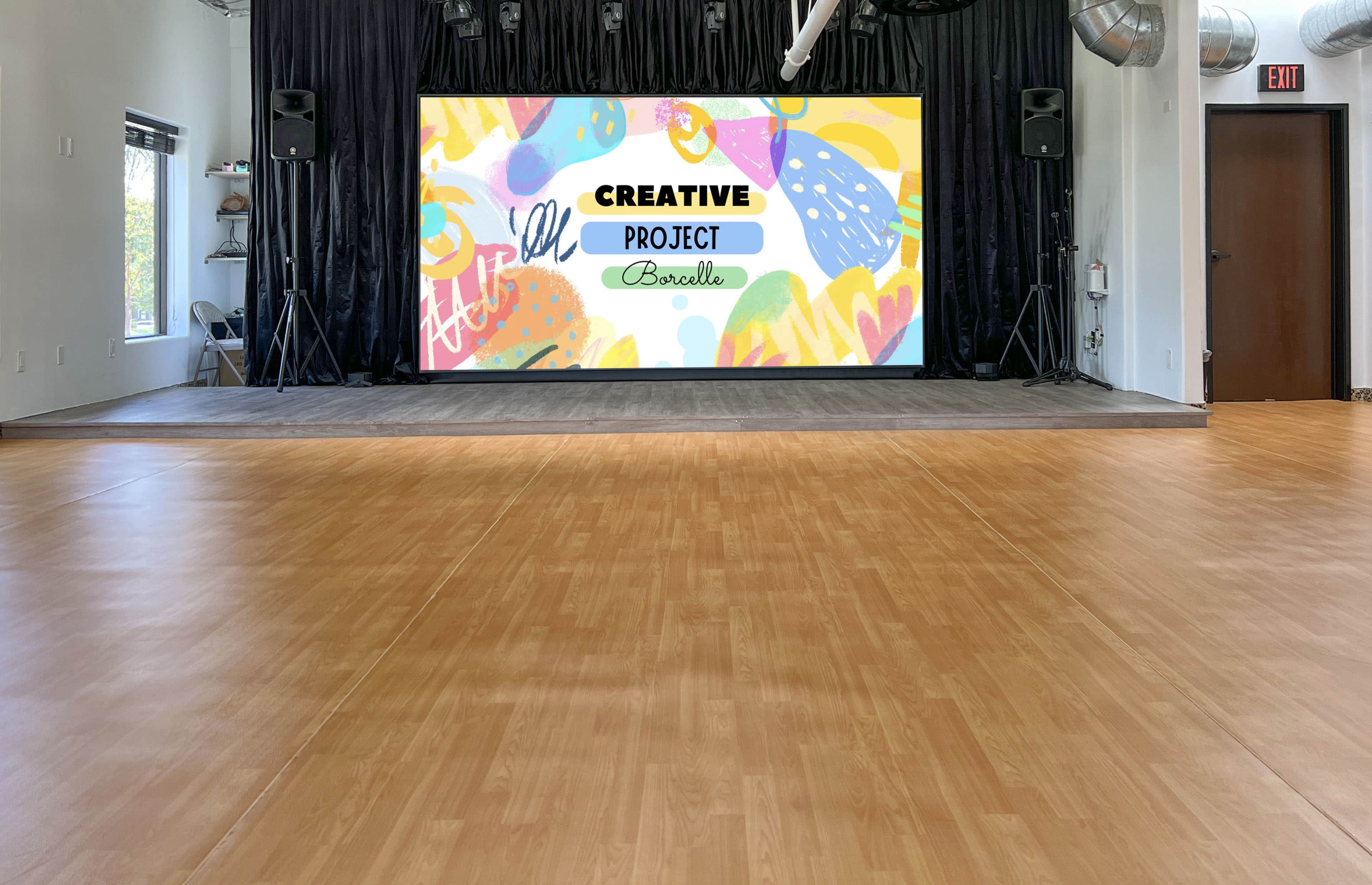 The image shows a spacious room with a large screen displaying colorful artwork and the words "Creative Project Borello," flanked by speakers on either side.