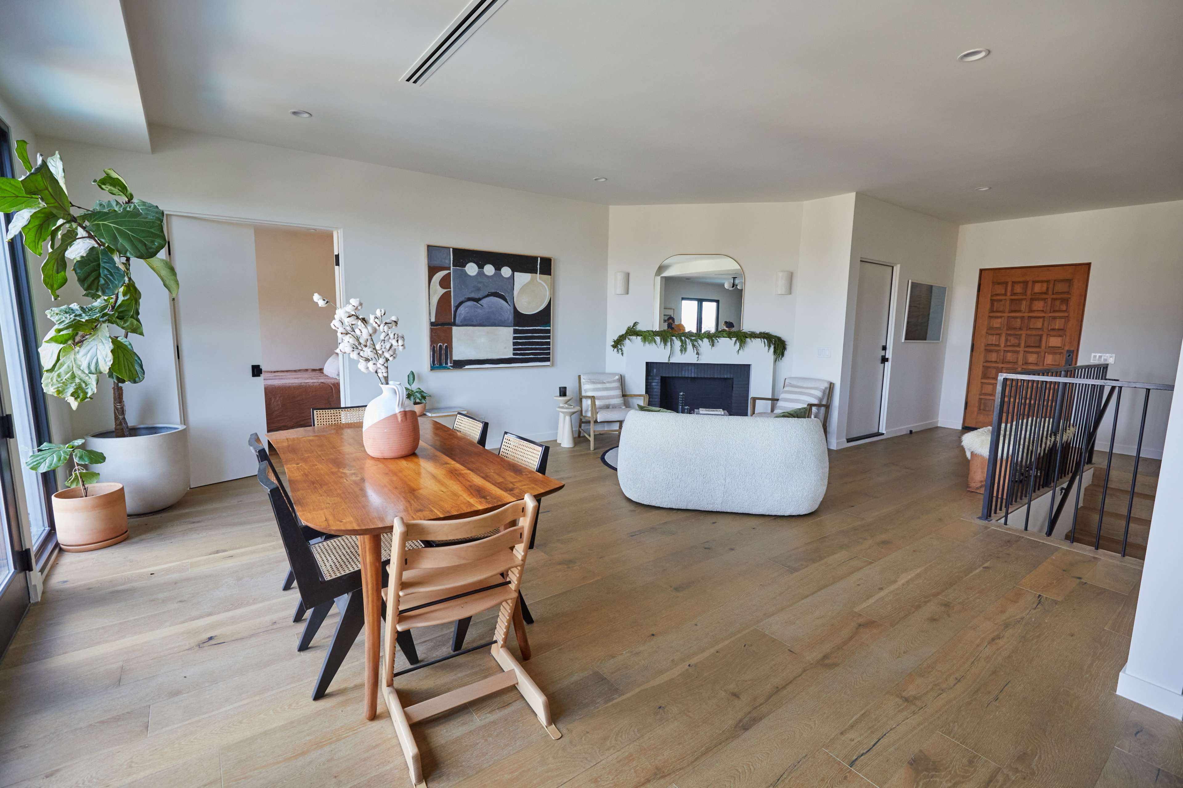 The room features a spacious open layout with a dining table, a sofa, and a large window, allowing ample natural light.