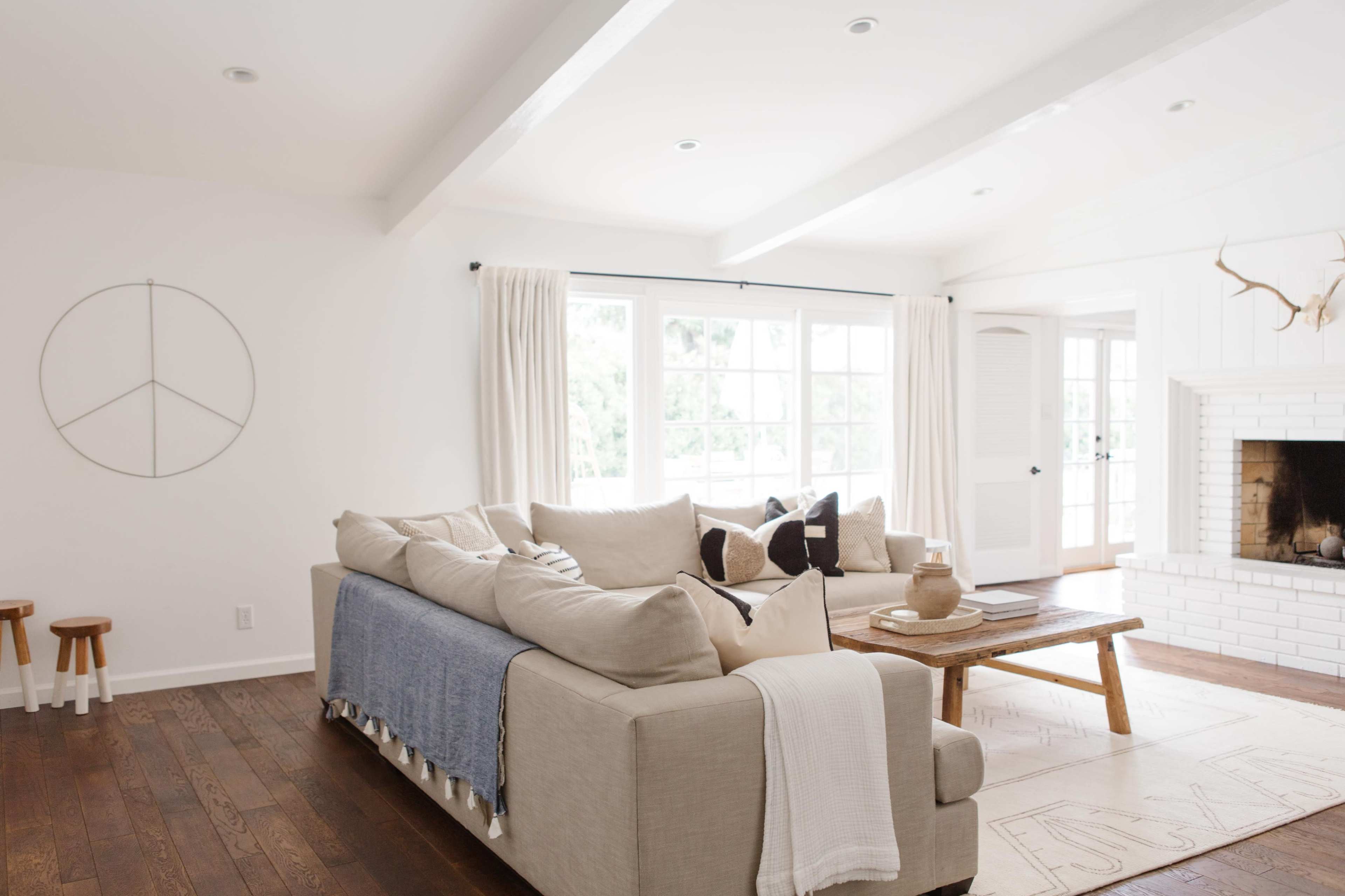 A spacious living room features a large sectional sofa, a wooden coffee table, and a fireplace, with ample natural light coming through large windows.