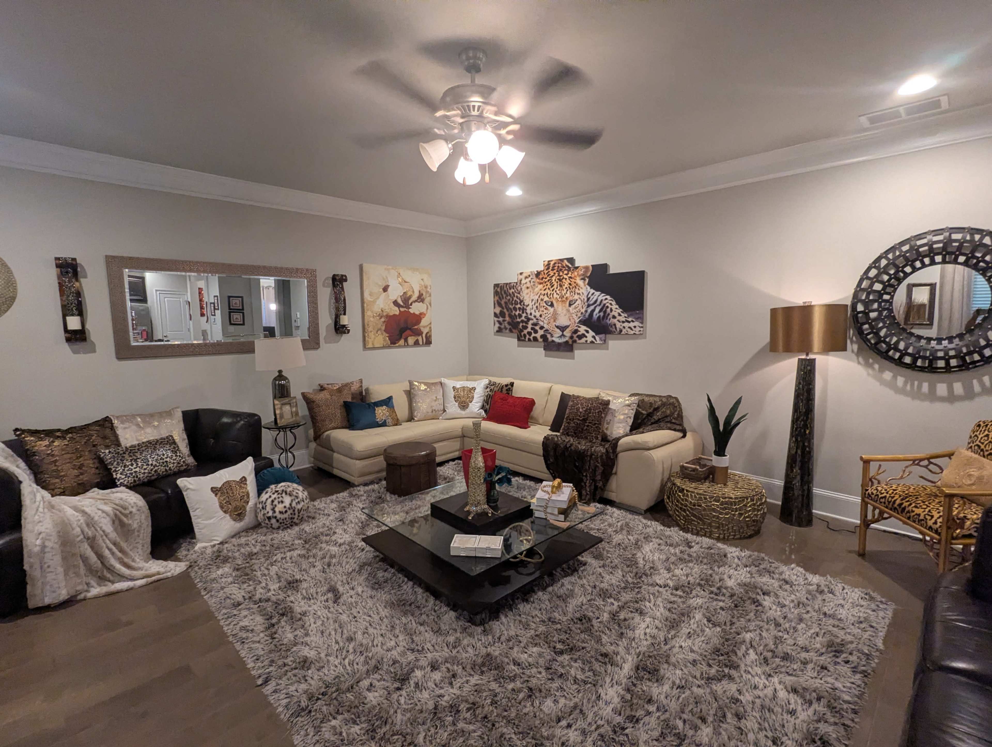 The living room features a sectional sofa, a coffee table, and various decorative elements, including animal-themed artwork and a large area rug.