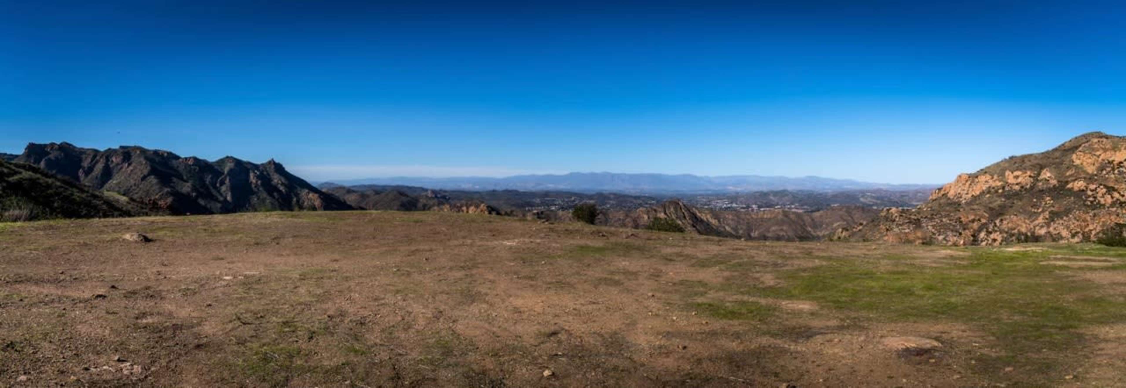 A panoramic view of a mountainous landscape under a clear blue sky.