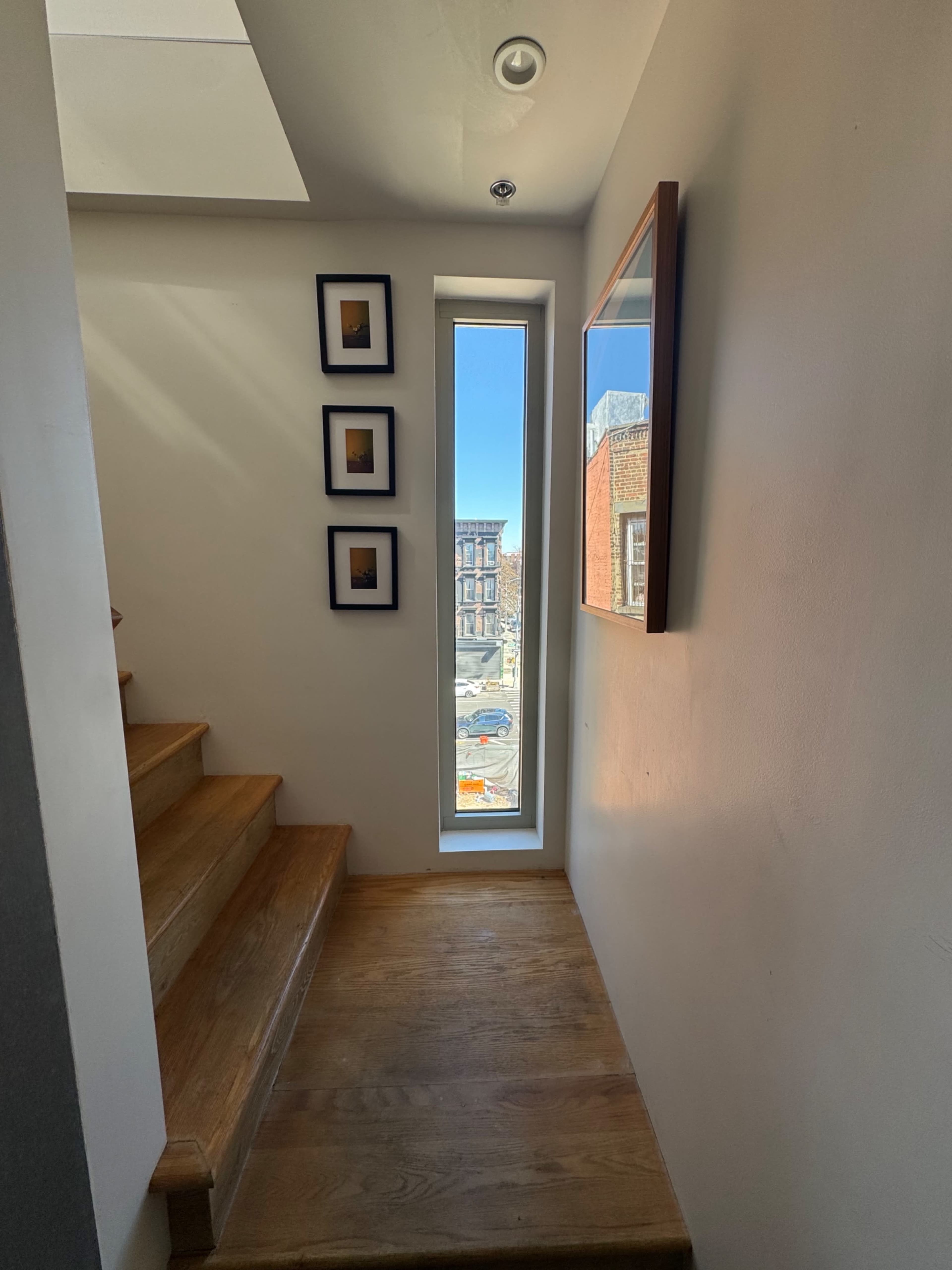 A narrow stairway leads to a window with a view of the street, flanked by framed pictures on one wall.