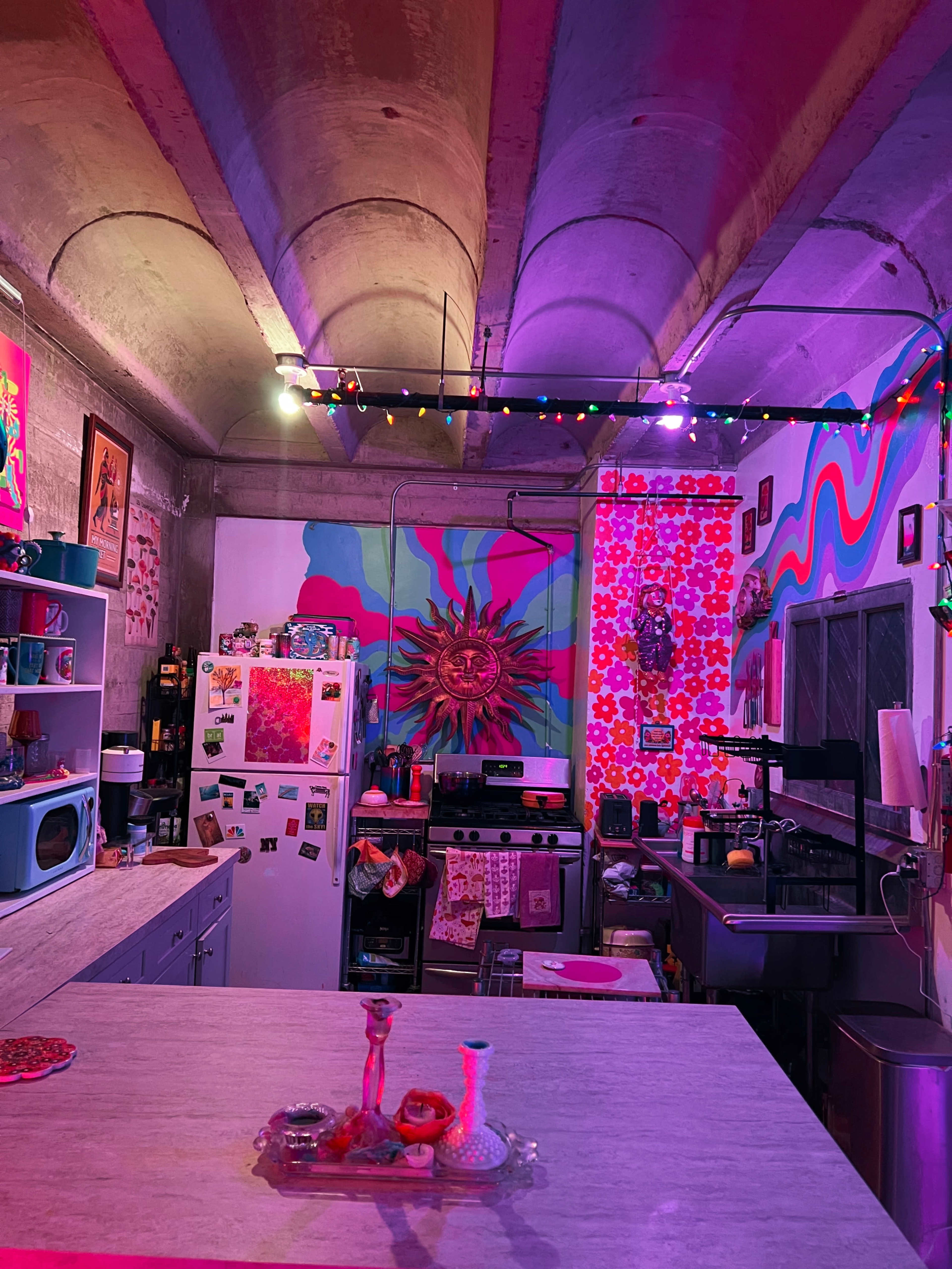 The kitchen features colorful murals and decorations, with vibrant lighting and various kitchen appliances arranged on counters.