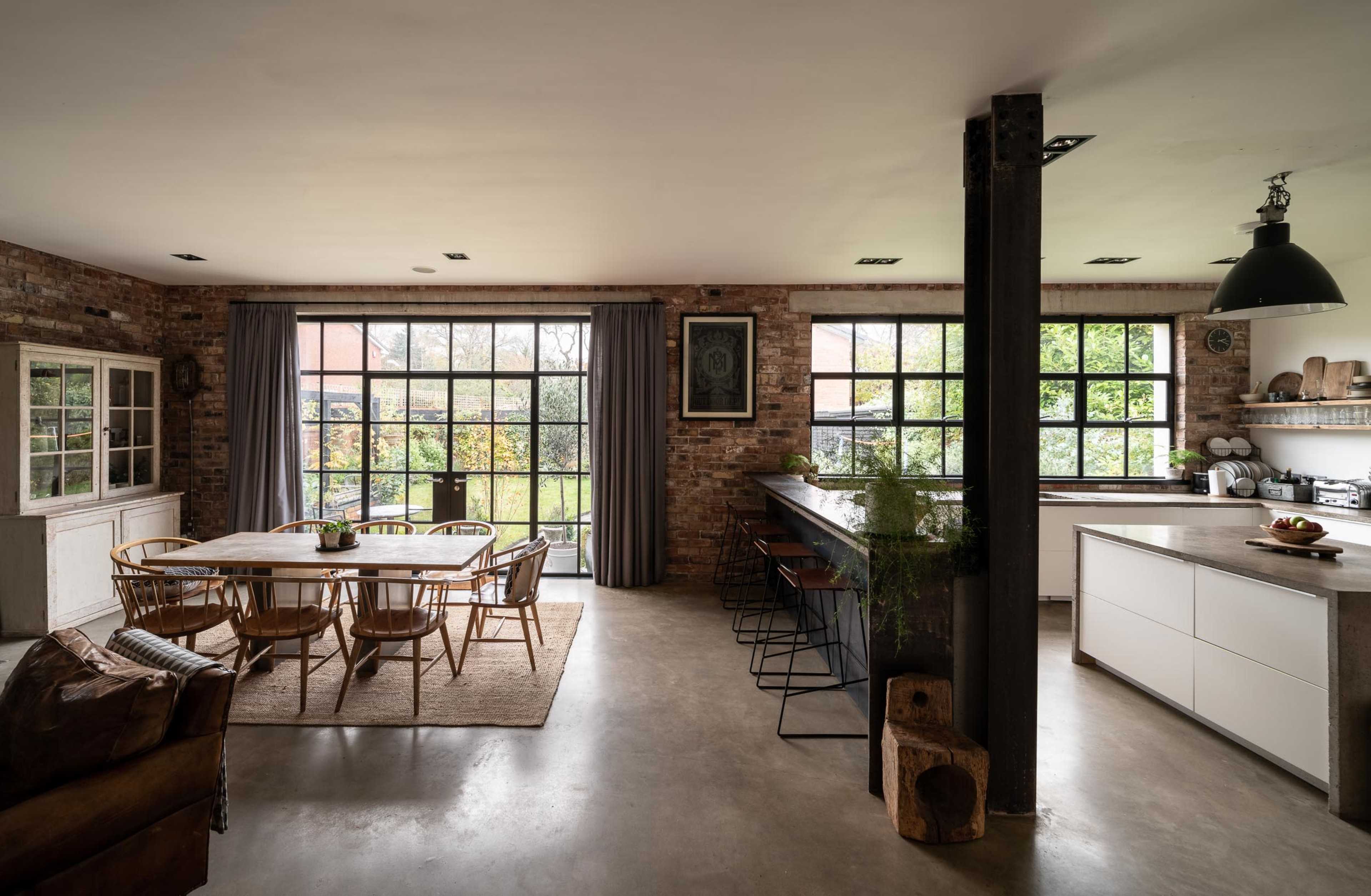A spacious, modern kitchen and dining area with large windows and a mix of rustic elements and contemporary furniture.