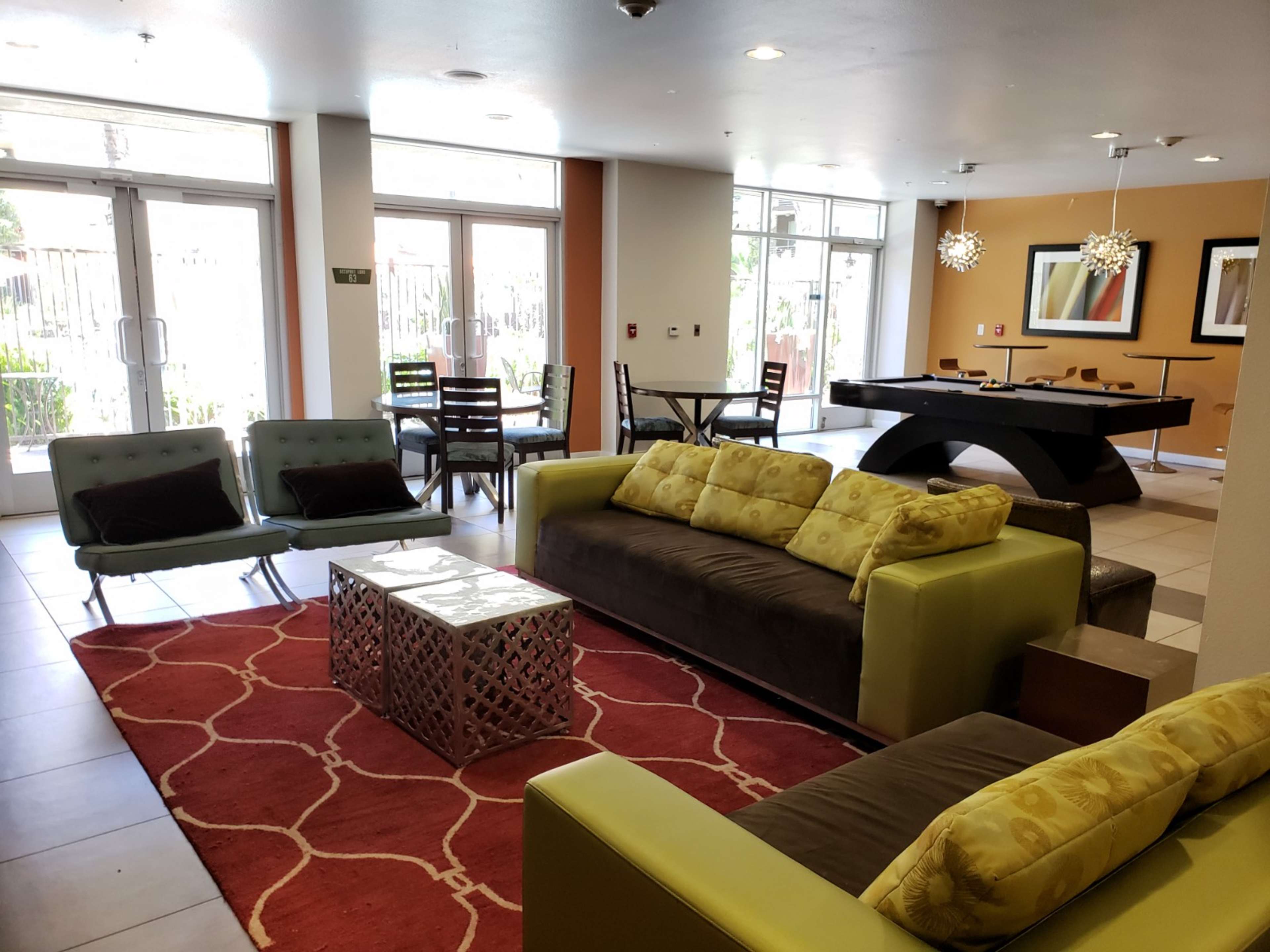 A modern lounge area with a mix of seating, including two sofas, a coffee table, and a dining space in the background.