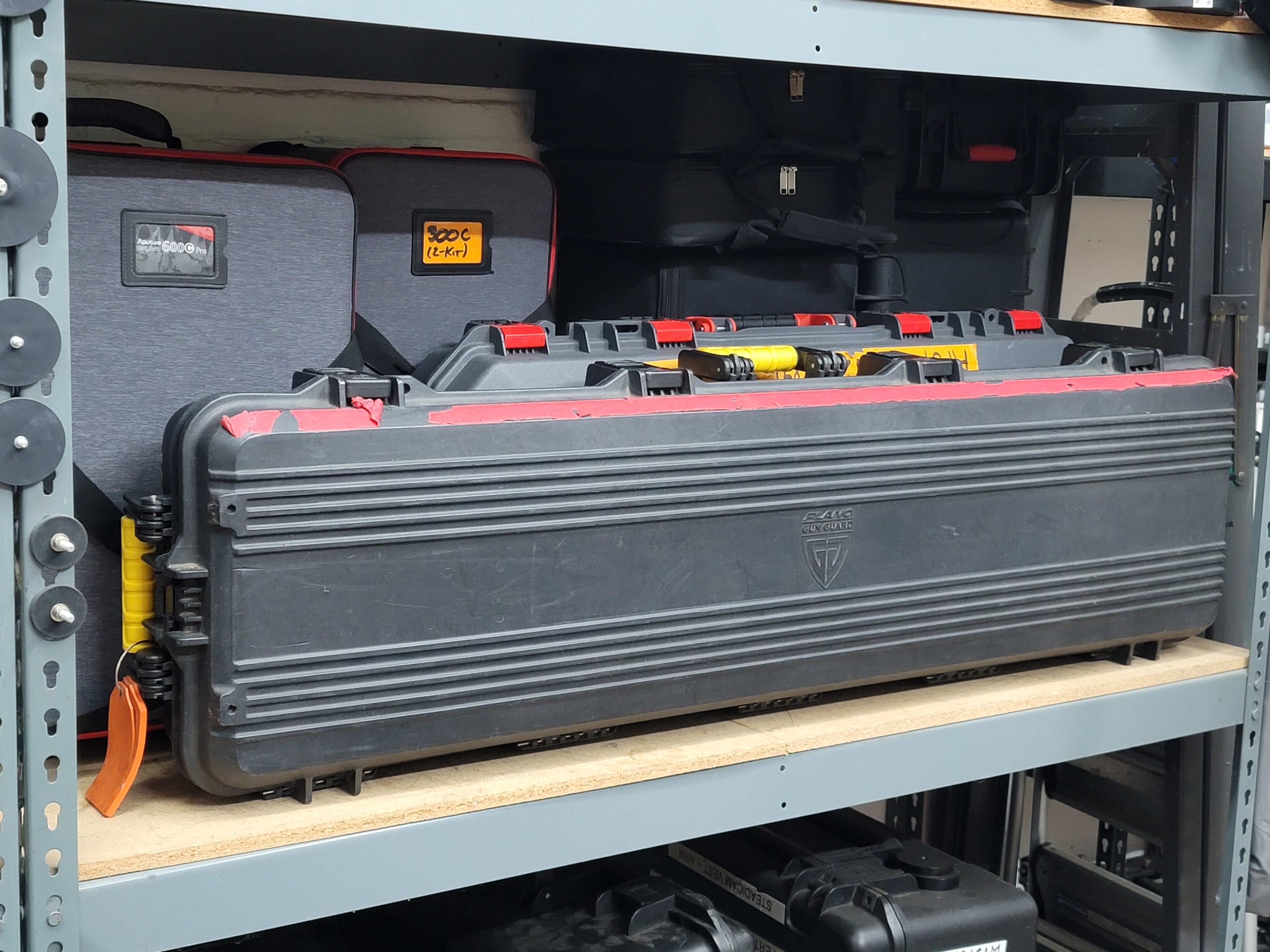 A black protective case is prominently displayed on a shelf, flanked by smaller equipment bags and additional containers.