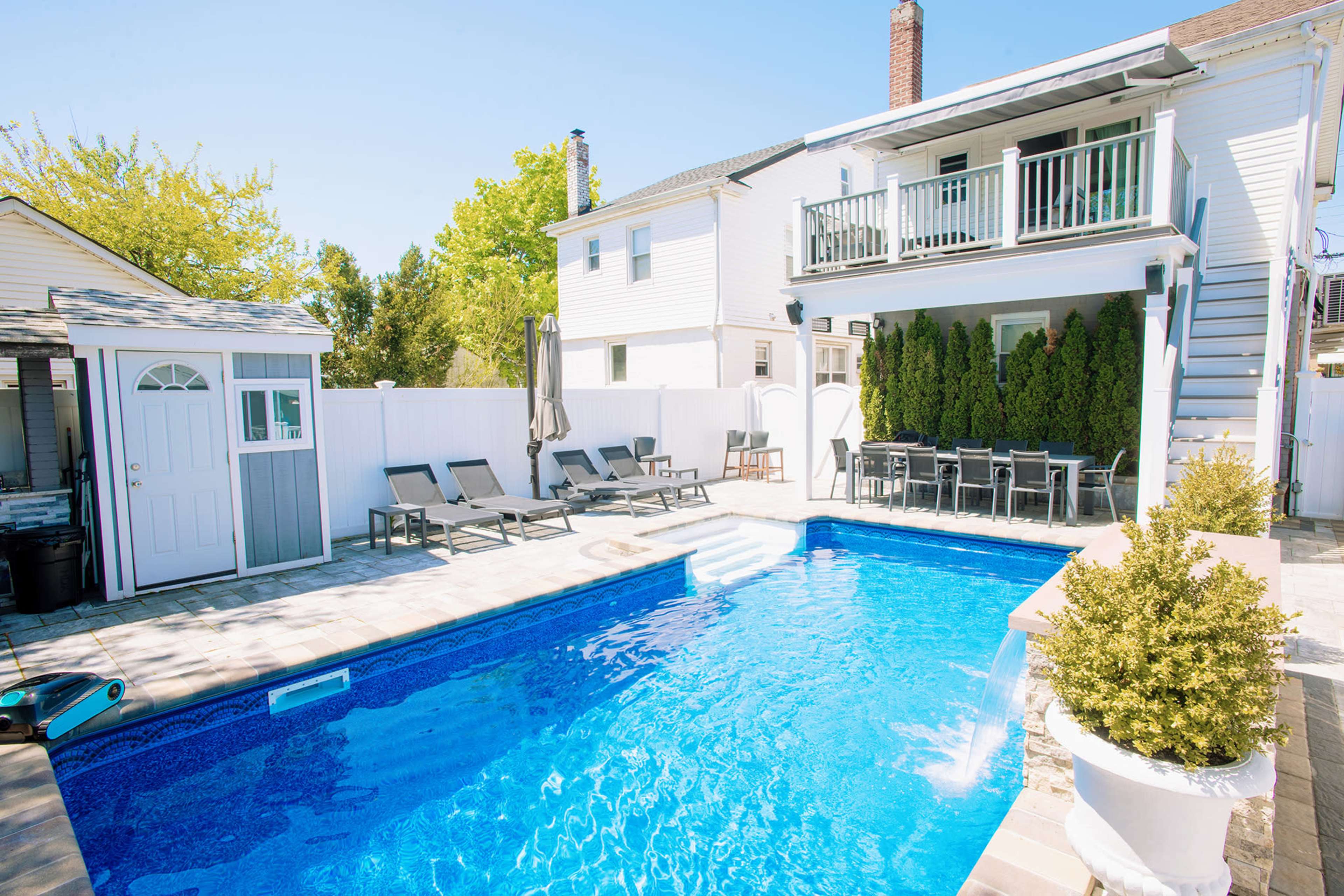 The image shows a backyard with a swimming pool, patio furniture, and a two-story house in the background.