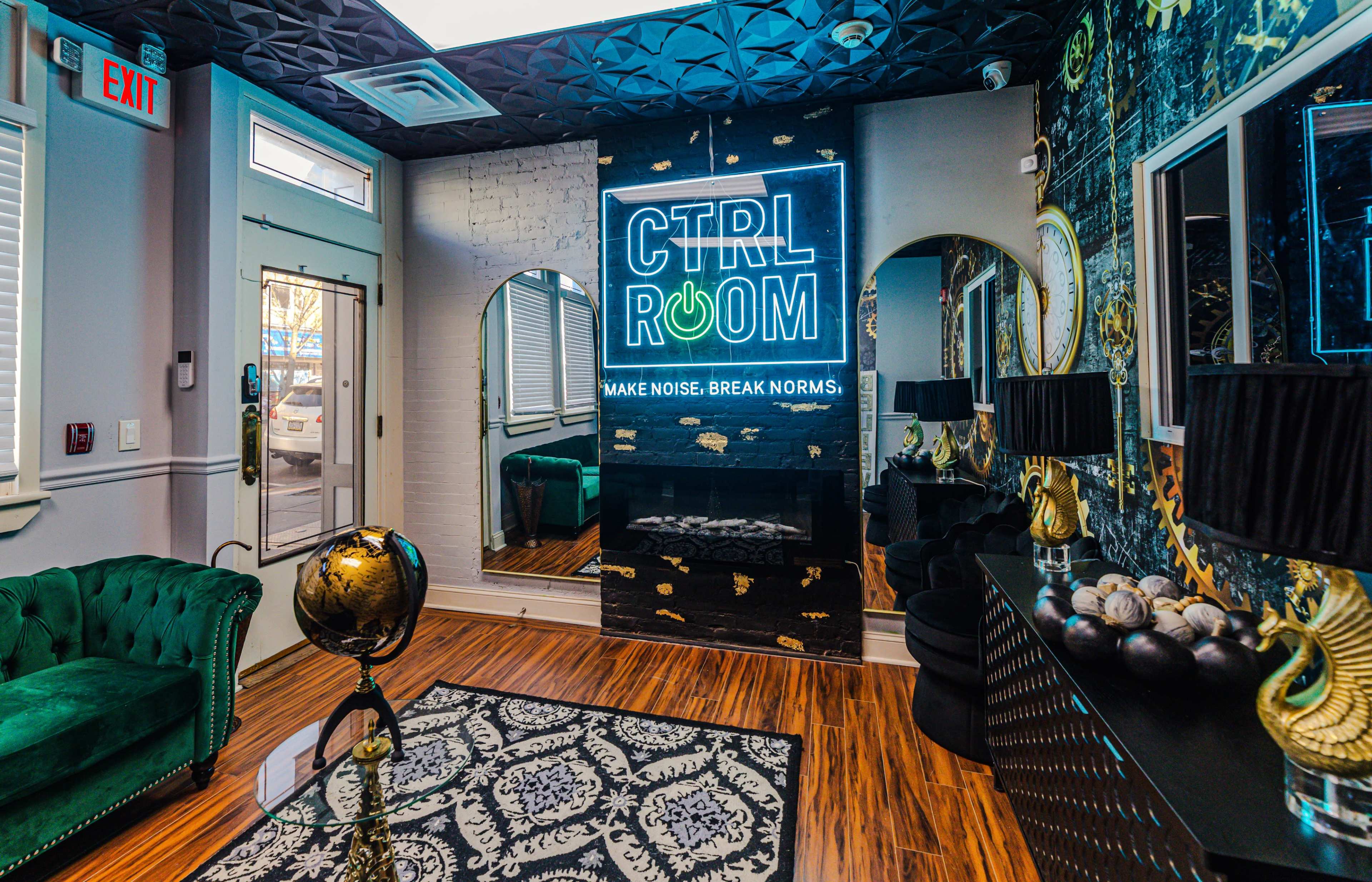 The image features a modern room with a neon sign reading "CTRL ROOM," a decorative fireplace, a dark patterned wall, and elegant furnishings, including a green couch and a globe sculpture.