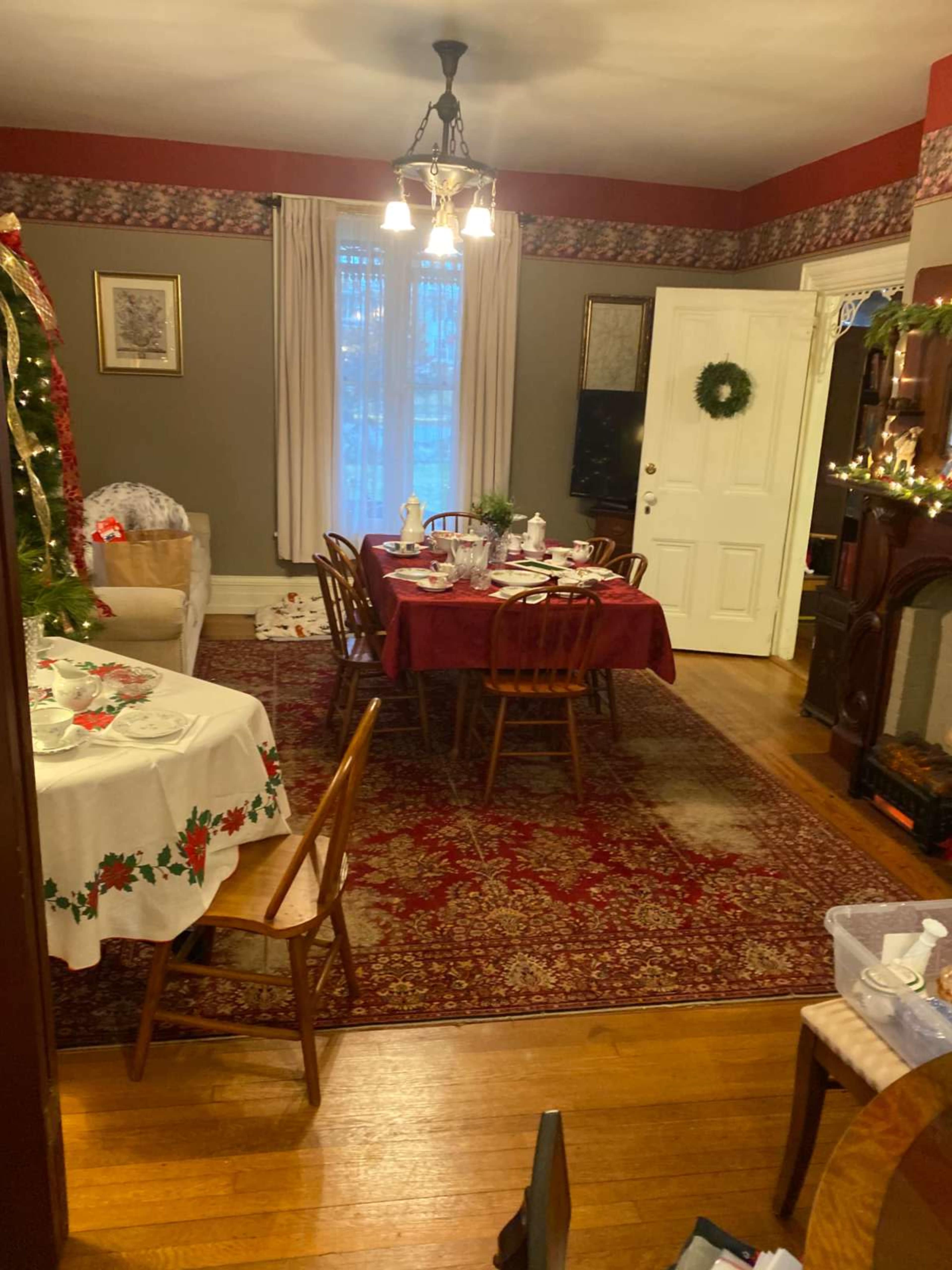 The image shows a dining area with a set table adorned with holiday-themed decorations, a couch, and a decorative fireplace.