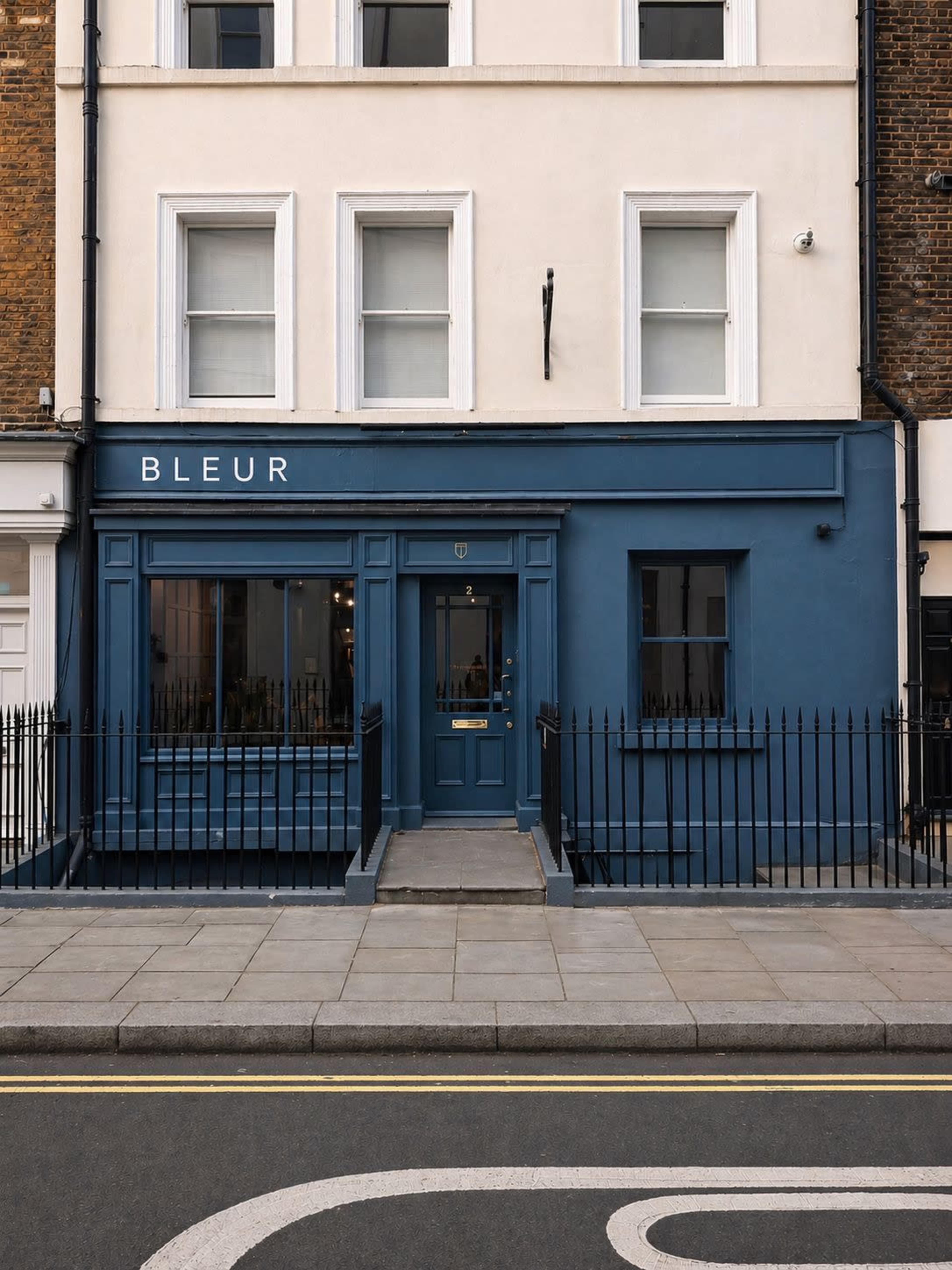 The image features a blue storefront named "BLEUR" with a white facade and several large windows, situated on a city street.