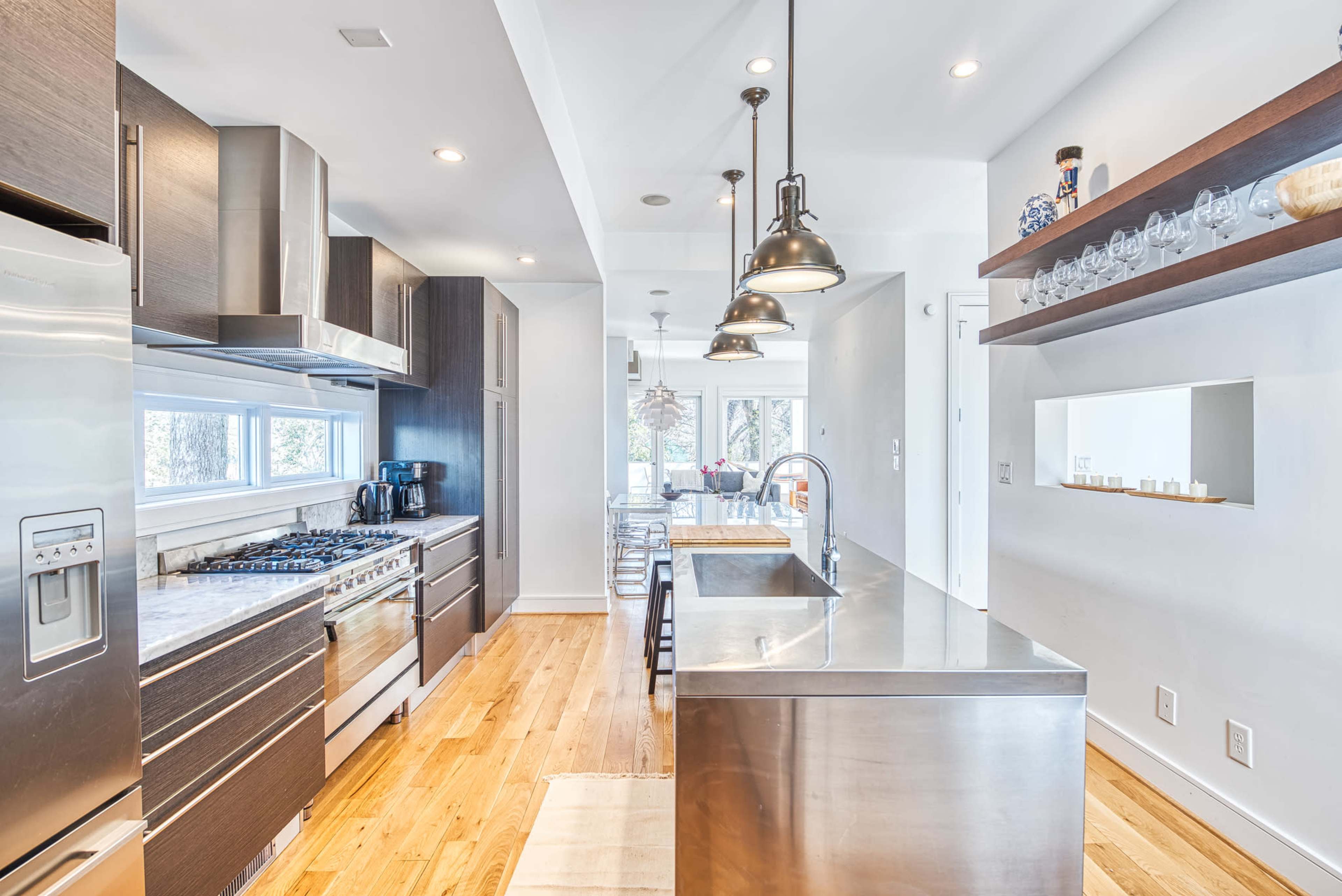 A modern kitchen features stainless steel appliances, wooden cabinets, and a central island with seating.