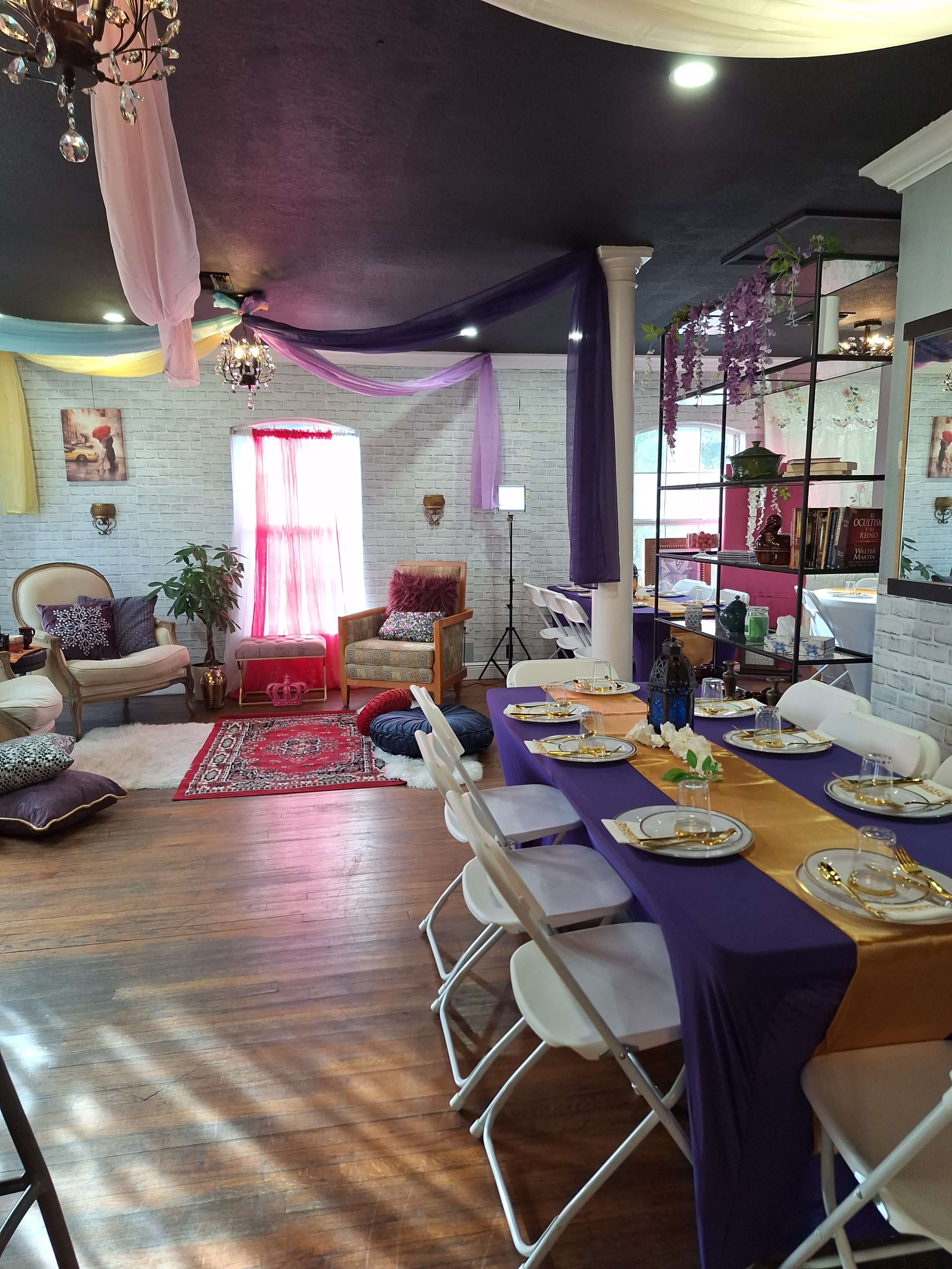 A decorated room with a dining table set for a meal, surrounded by plush seating areas and vibrant drapery.